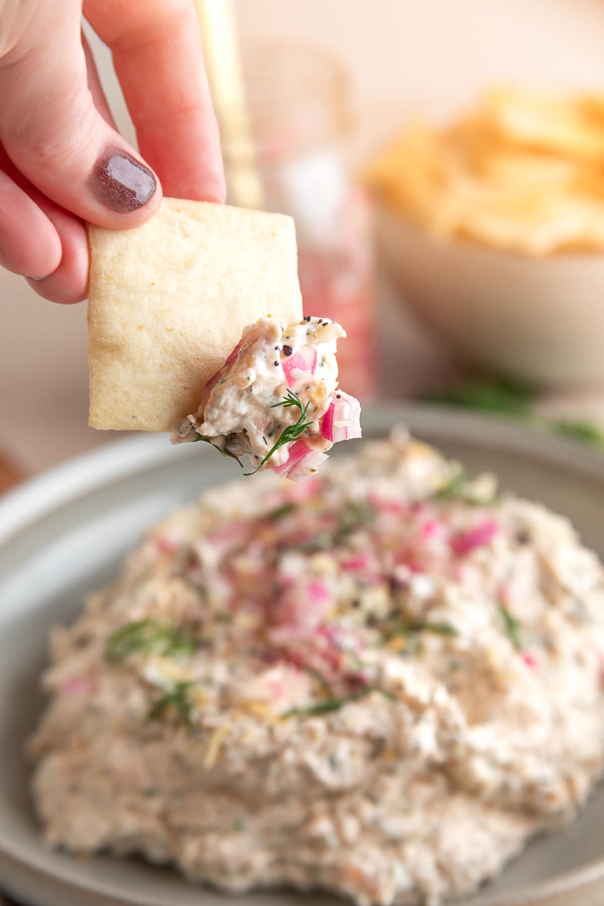 Smoked salmon dip being finished with everything bagel seasoning and pickled red onions just before serving.