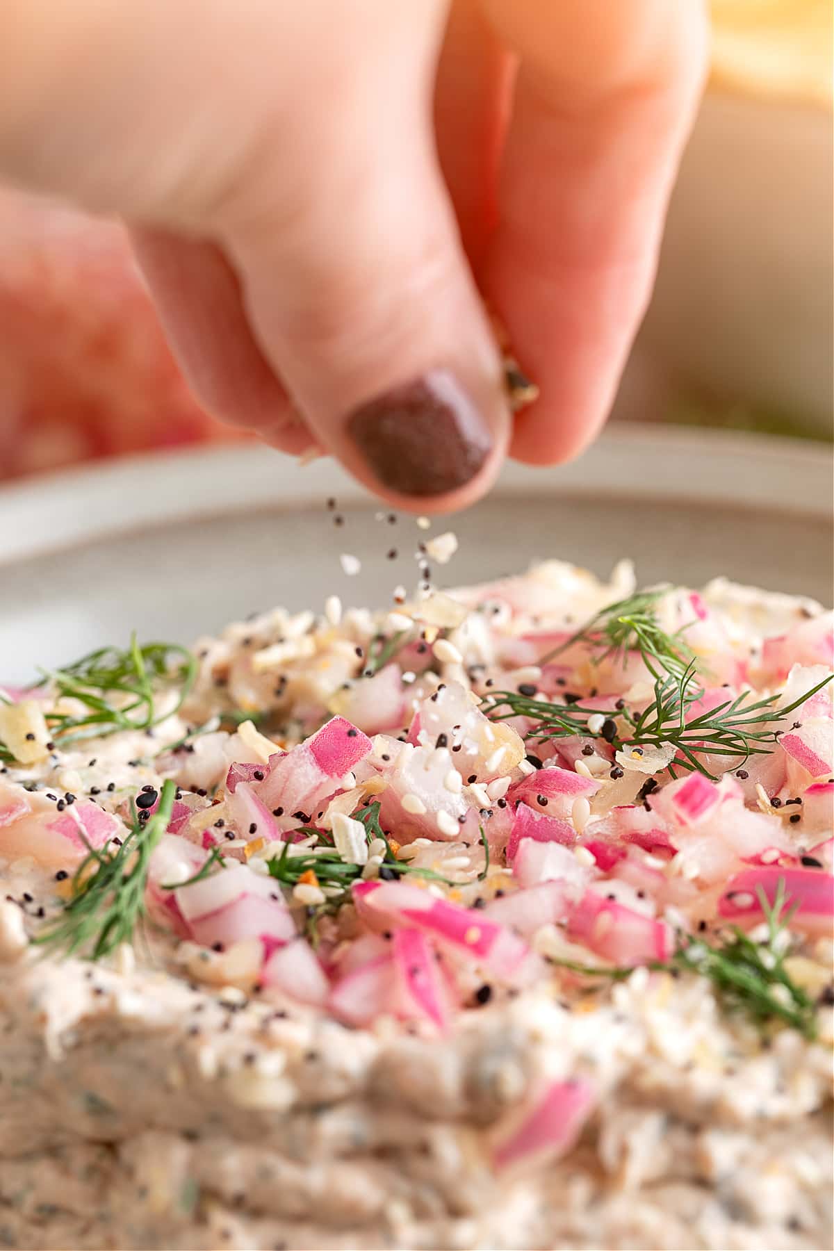 Smoked salmon dip scooped with a pita chip, showing the creamy texture with pickled red onions and fresh dill.