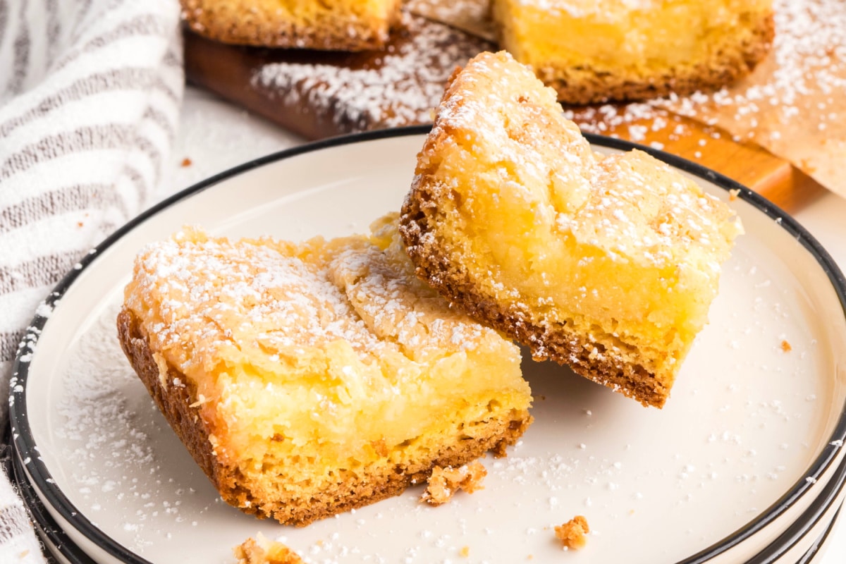 Gooey butter cake bars with cream cheese topping and buttery cake base. Gooey butter cake bars with a rich cream cheese topping and buttery base, baked until golden and dusted lightly with confectioners’ sugar.