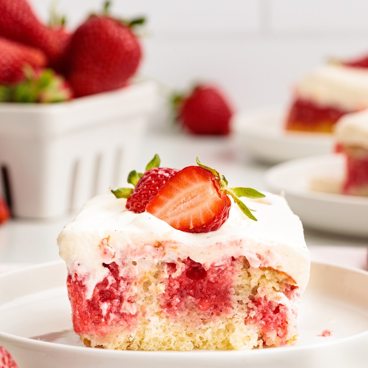 Strawberry poke cake with jello-soaked cake layers and whipped cream cheese frosting.