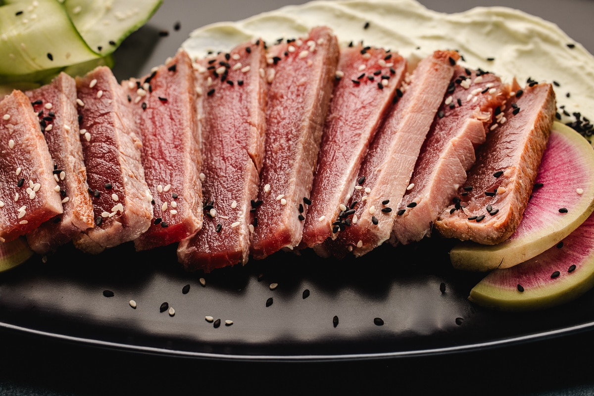 Rare ahi tuna sliced against the grain with black and white sesame seeds and watermelon radish