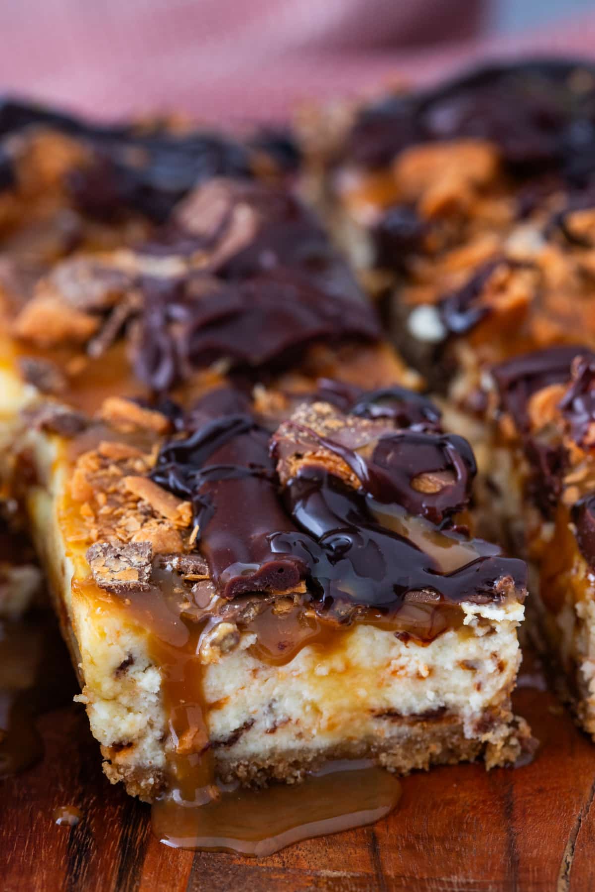 Caramel cheesecake square with chopped Butterfinger pieces and melted chocolate on topCaramel cheesecake square with chopped Butterfinger pieces and melted chocolate on top