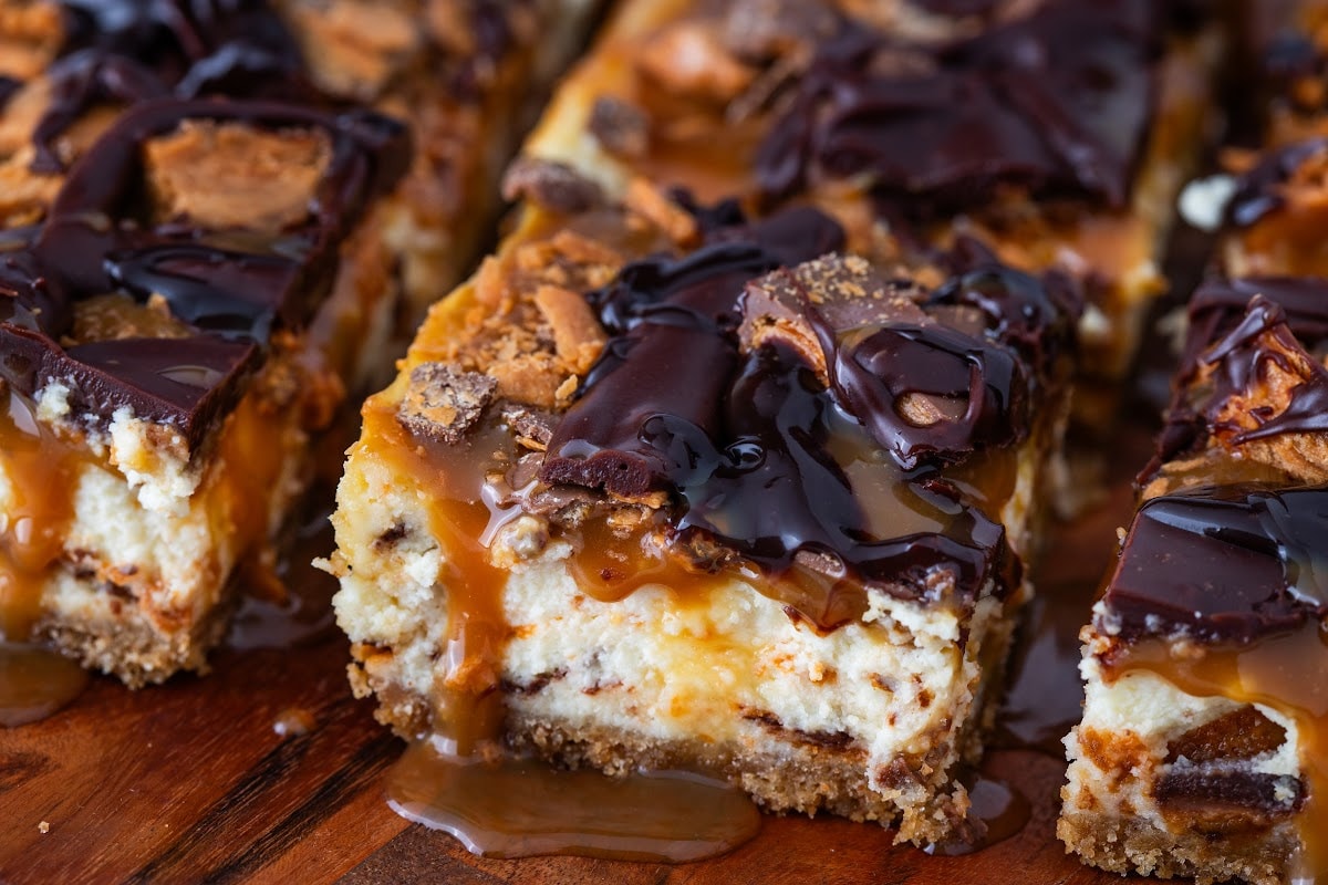 Close-up of Butterfinger Caramel Cheesecake Bars with caramel drizzle and chopped candy pieces