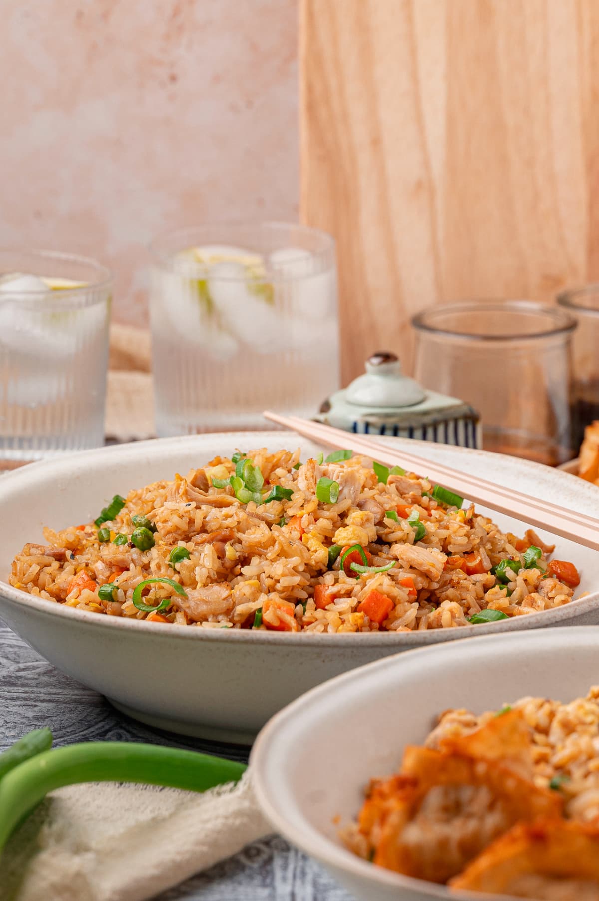 Homemade fried rice with chicken, eggs, peas, carrots, and green onions served in a wide bowl