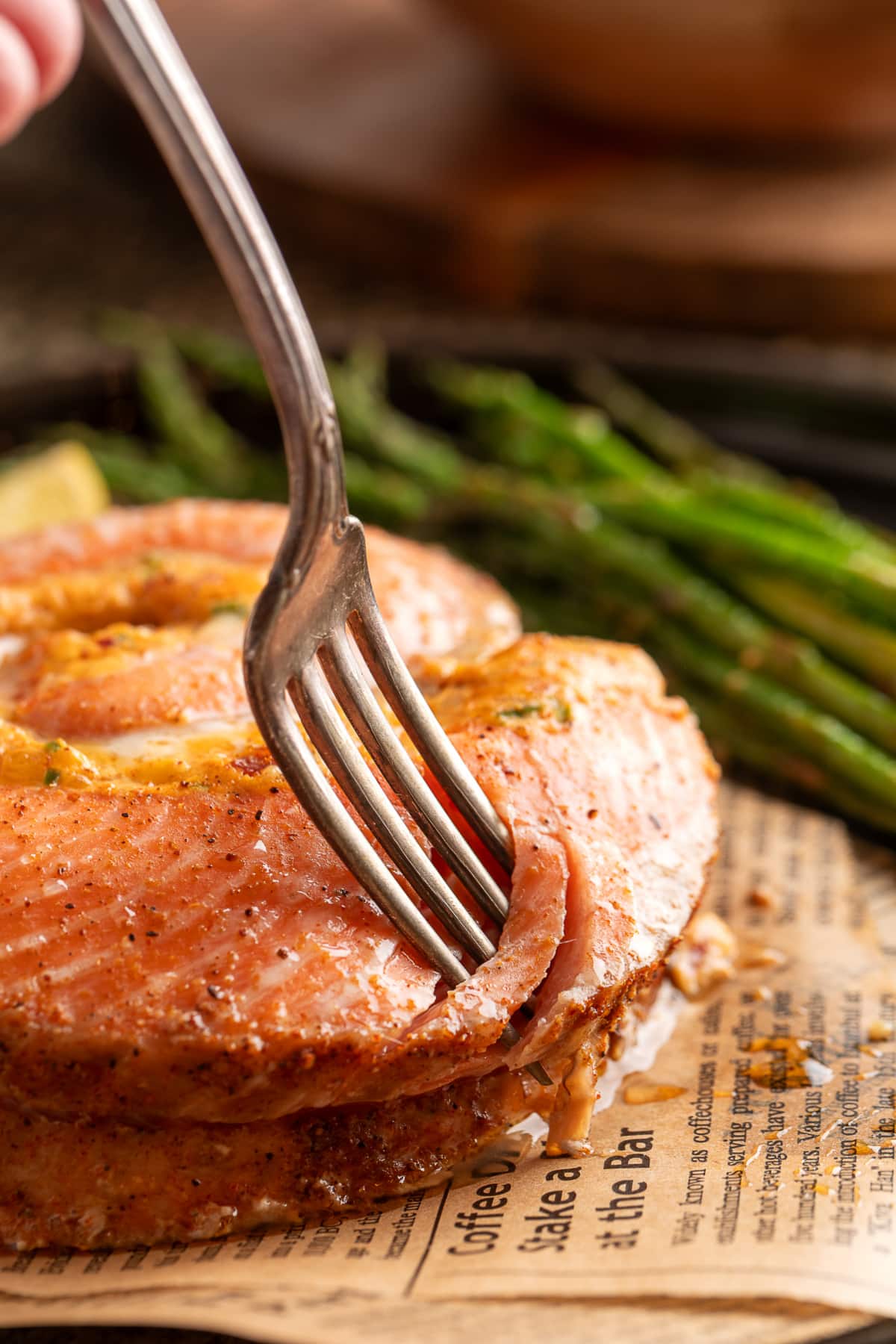 Close-up of a fork cutting into a baked stuffed salmon pinwheel, showing the tender salmon and creamy jalapeño popper-style center. Fork cutting into a baked salmon pinwheel with creamy jalapeño popper filling