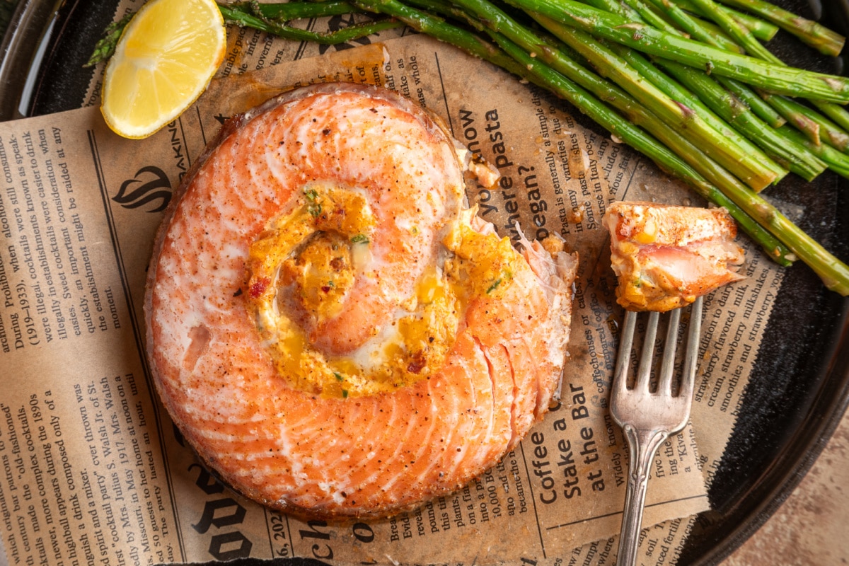Top-down close-up of a baked salmon pinwheel showing the creamy jalapeño popper filling, served with roasted asparagus and lemon. Close-up of baked stuffed salmon pinwheel with jalapeño popper-style filling