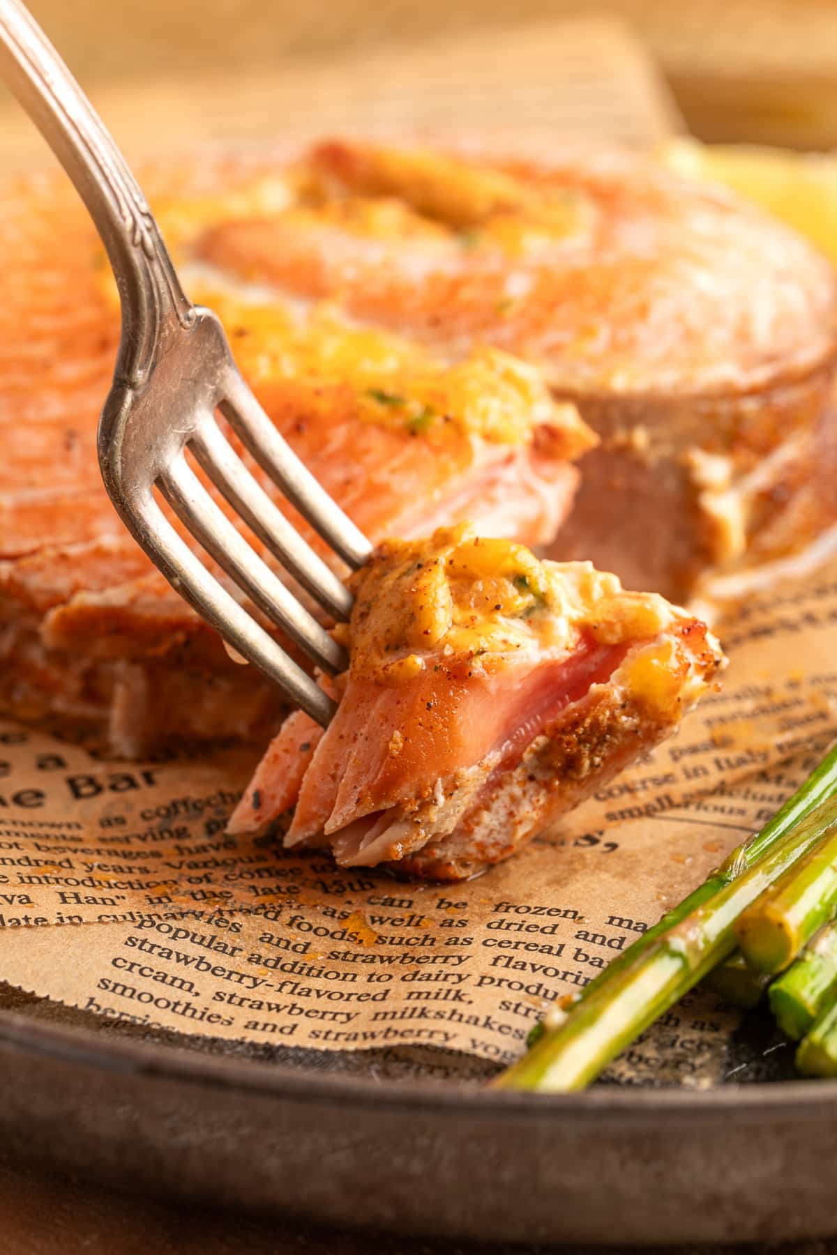 Close-up of a fork lifting a flaky bite from a baked salmon roll, showing the creamy jalapeño popper-style filling inside the salmon. Chipotle jalapeño popper stuffed salmon rolls with a fork lifting a flaky bite