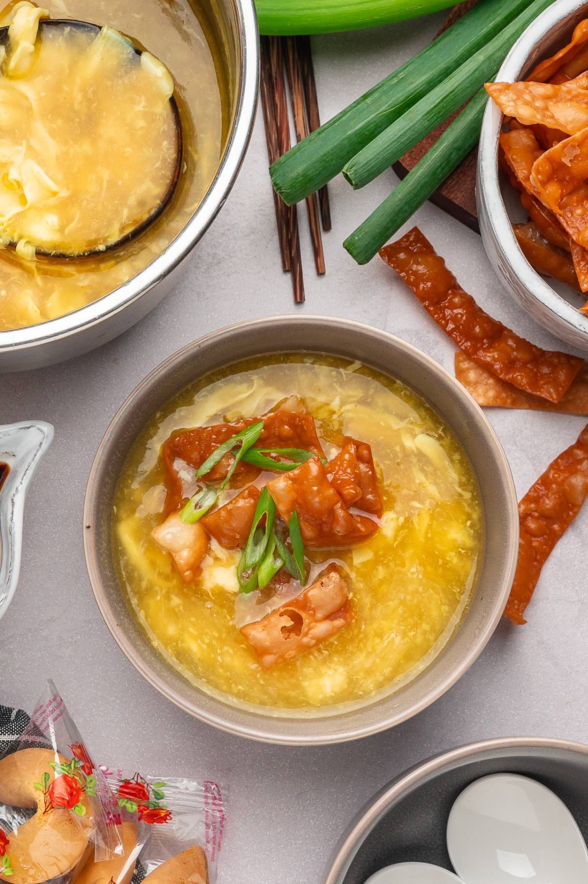 Bowl of egg drop soup finished with golden fried wonton strips and scallions Egg drop soup with fried wonton strips served with soft egg ribbons and green onions