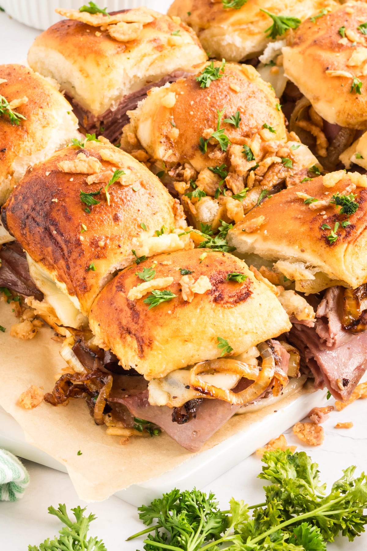 Close-up of baked roast beef sliders on soft sweet rolls with provolone cheese, caramelized onions, and crisp French-fried onions Roast beef sliders on Hawaiian rolls with melted provolone and caramelized onions