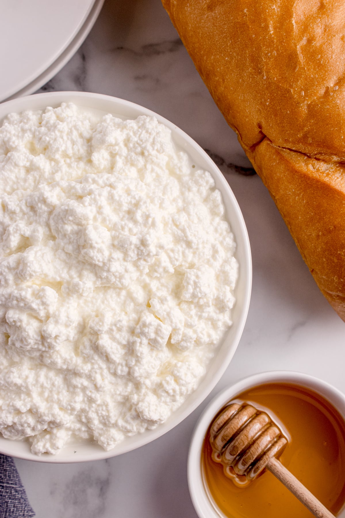 Bowl of fresh ricotta with soft curds, served alongside bread and honey Fresh ricotta in a bowl served with bread and honey