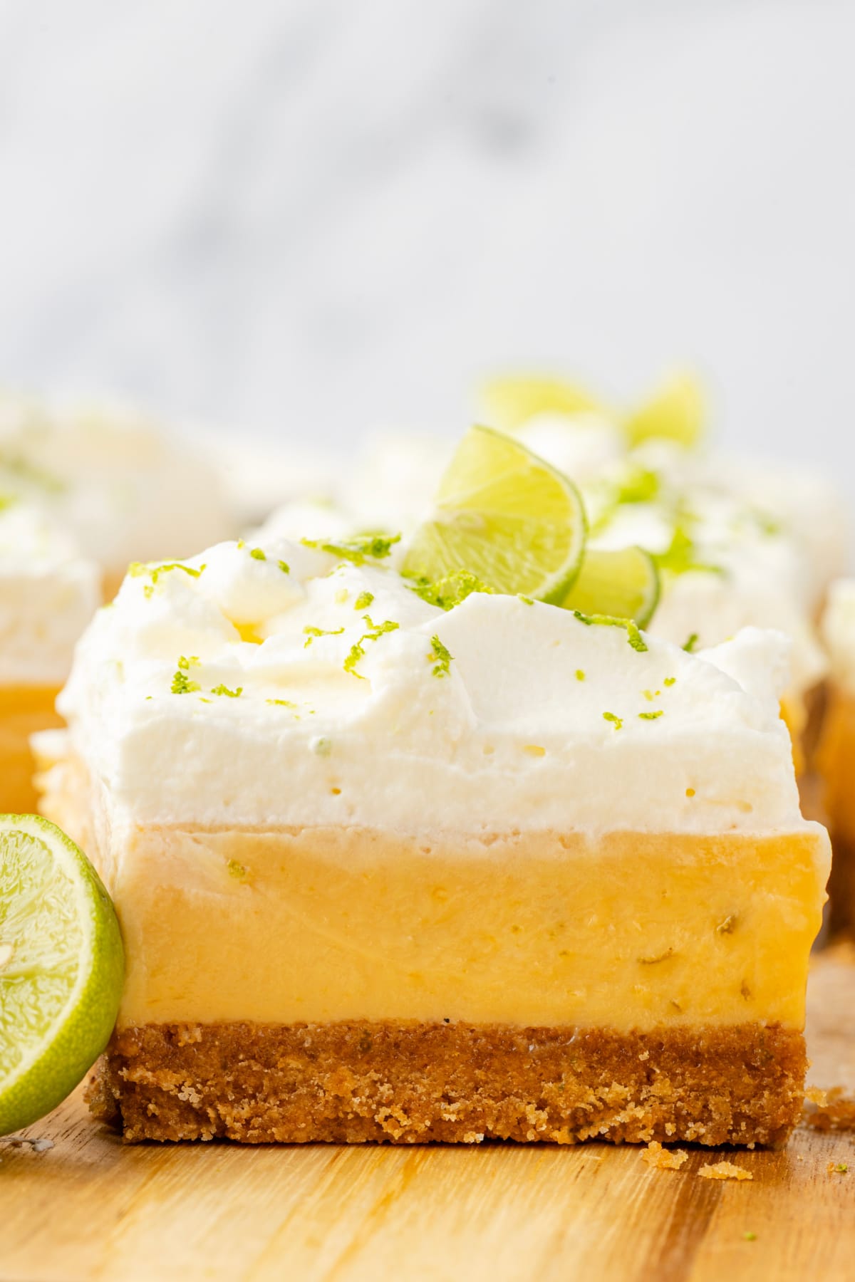 Layered slice with whipped cream Key lime bars with whipped cream topping, thick custard layer, and graham cracker crust