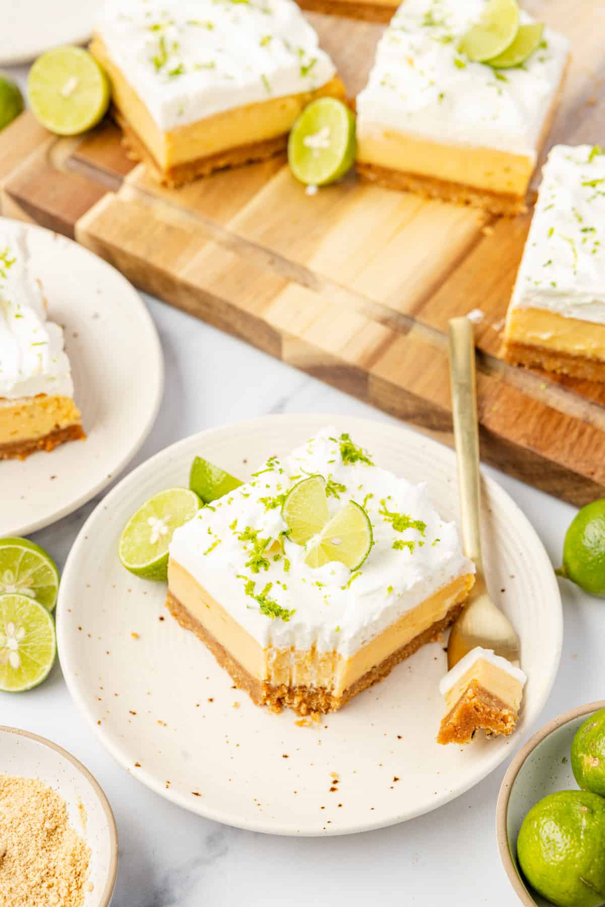 Plated slice with lime garnish Key lime bars served on plates with whipped cream topping, fresh lime zest, and graham cracker crust