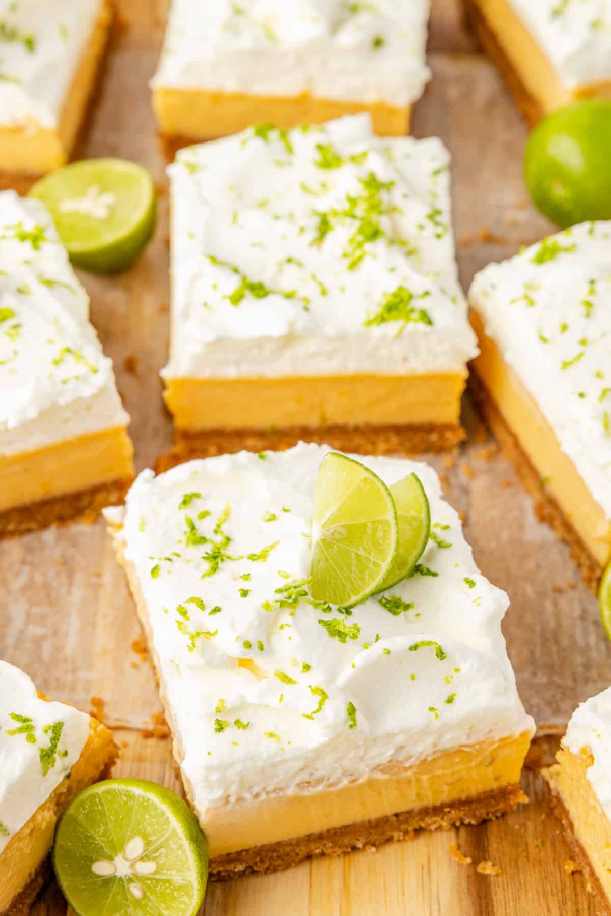Square slices topped with lime wedges Bakery-style key lime bars cut into squares with whipped cream and fresh lime garnish