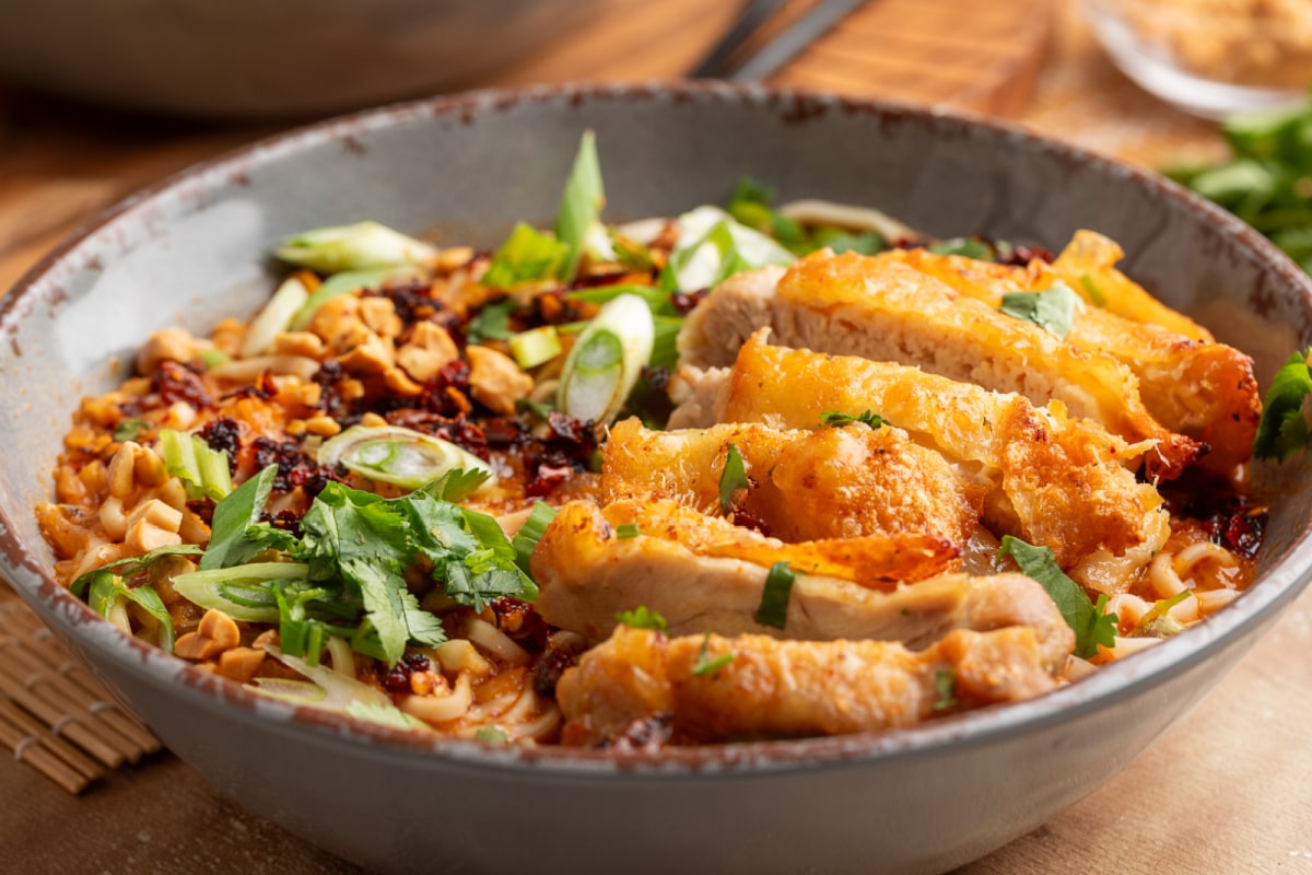 Panang curry ramen with crispy chicken close up Close-up of panang curry ramen with crispy chicken, coconut broth, chili crunch, scallions, and chopped peanuts