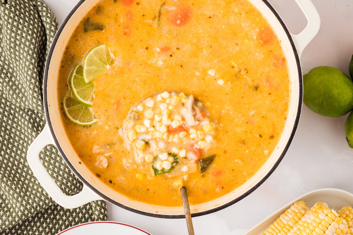 Overhead view of creamy poblano chicken and rice soup simmering with corn and lime slices