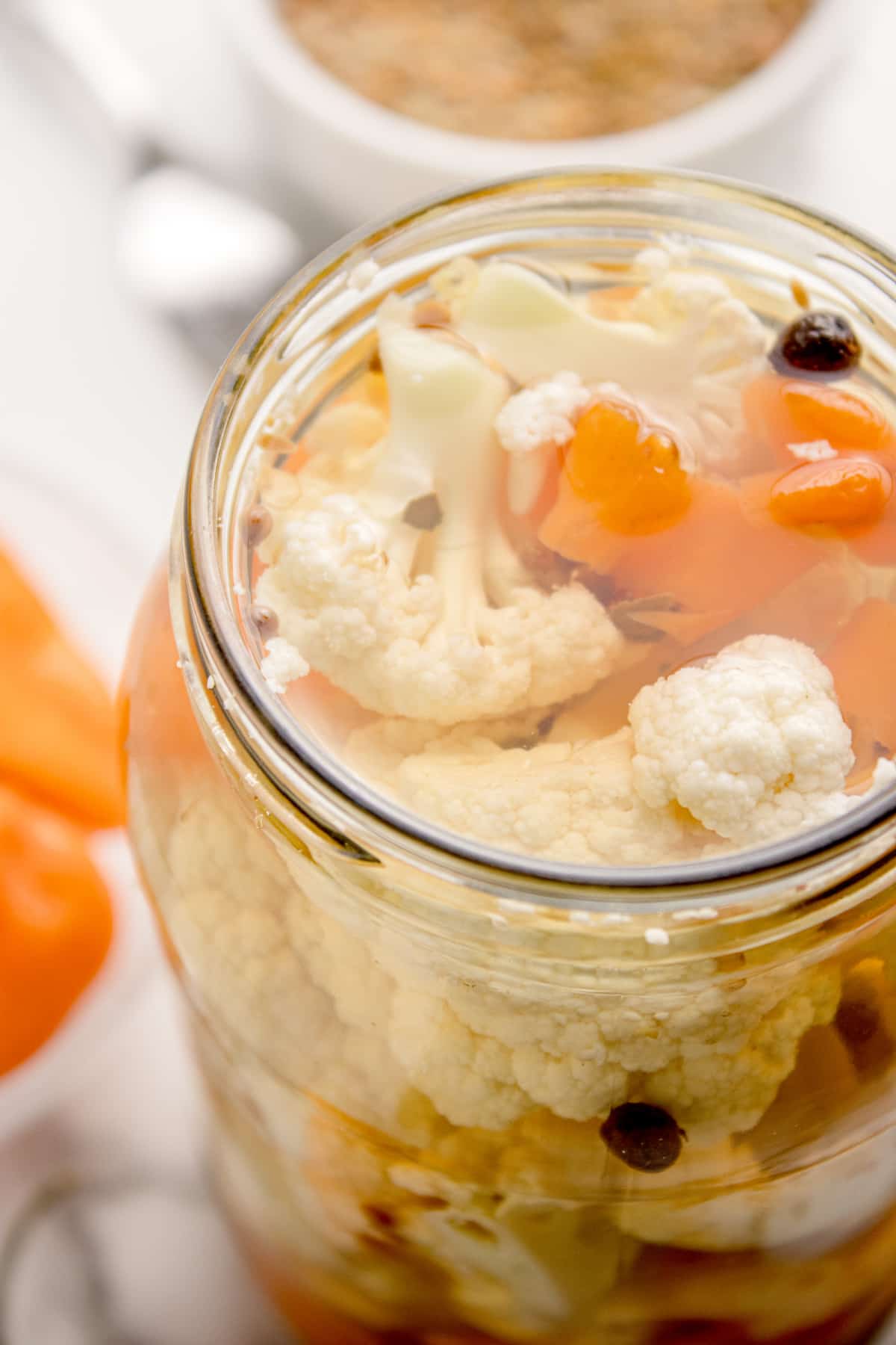 Detail of cauliflower refrigerator pickle with whole spices and peppers Close-up of spicy pickled cauliflower florets and habanero slices submerged in clear vinegar brine