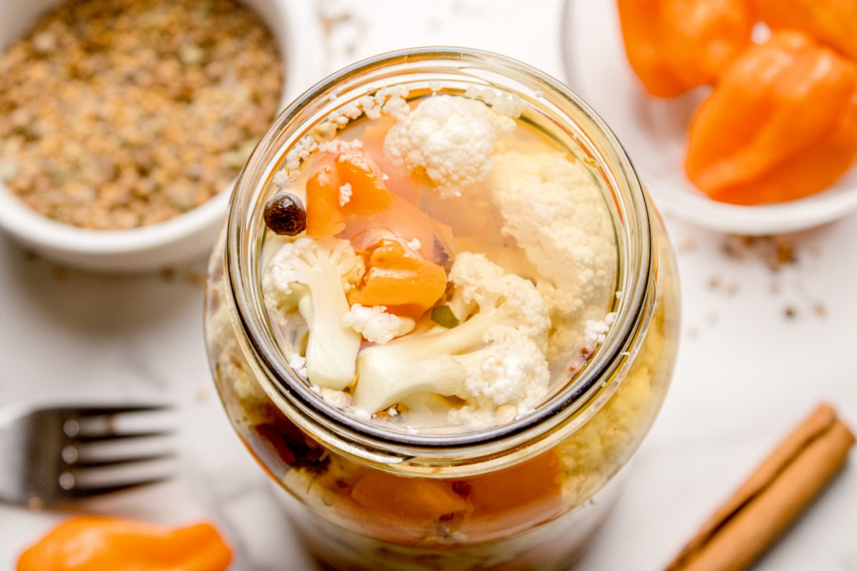 Top view of spicy refrigerator cauliflower pickles in glass jar Hot pickled cauliflower in vinegar brine with habanero slices and whole spices