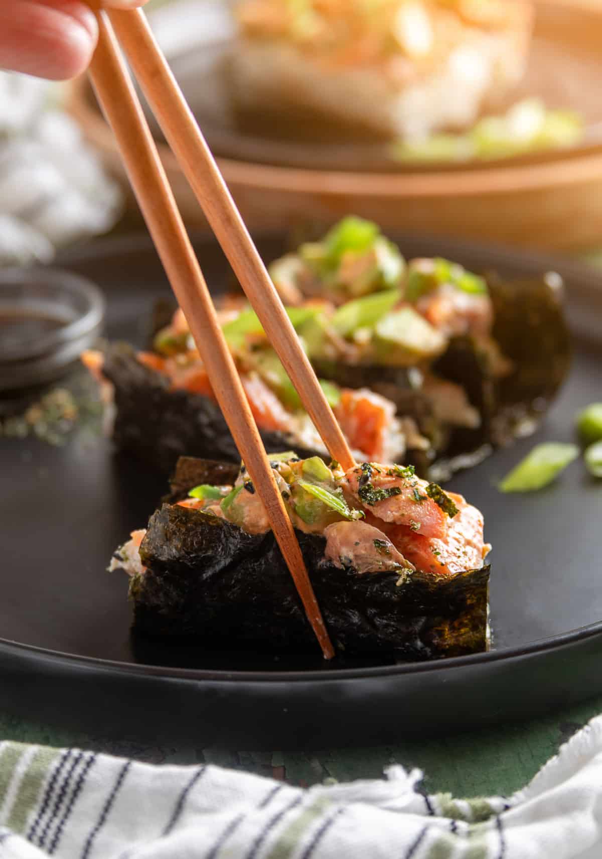 Scooped sushi bake wrapped in nori for serving. Sushi bake wrapped in nori and lifted with chopsticks