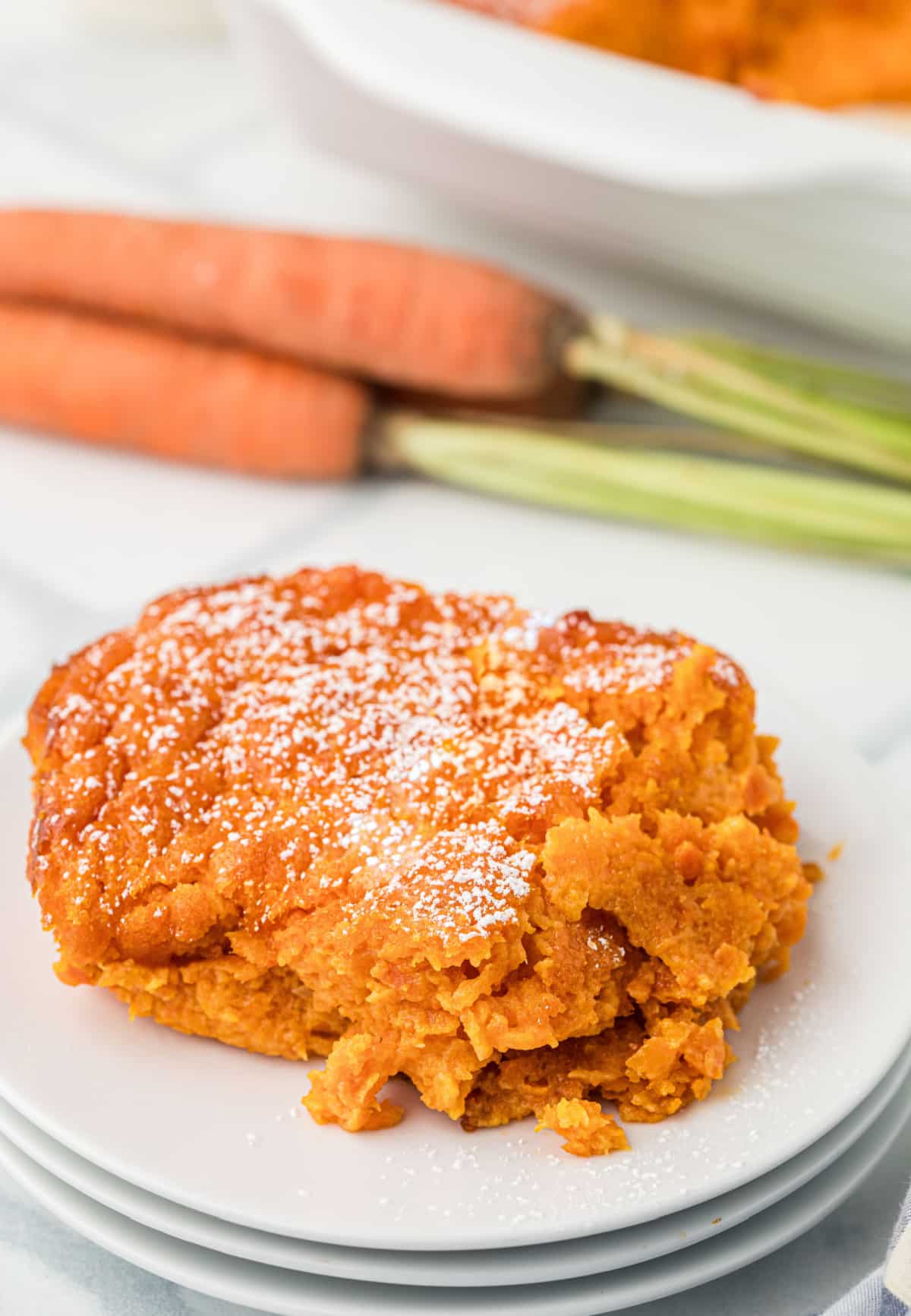 Southern carrot casserole slice served on plate Slice of sweet carrot casserole dusted with powdered sugar on white plate