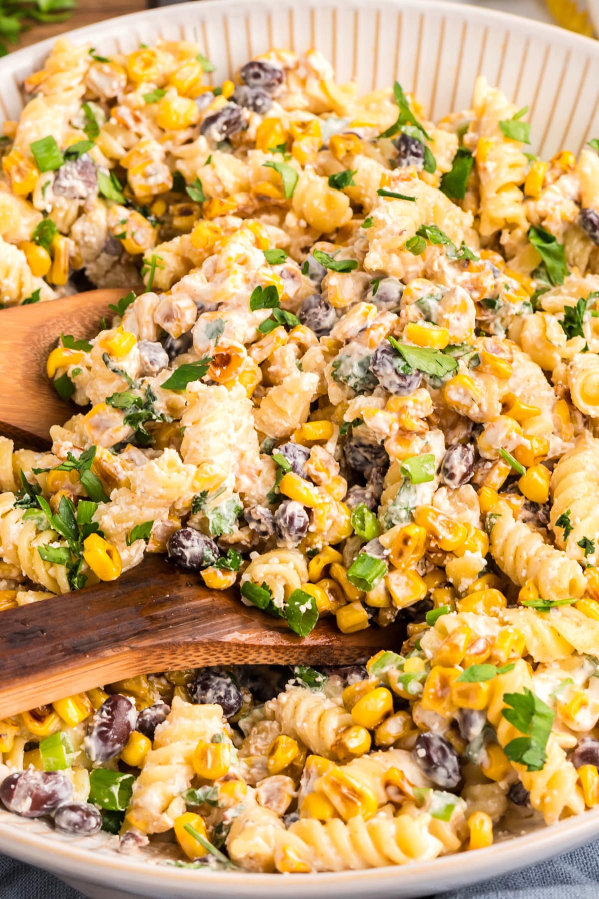 Close-up of creamy pasta salad with corn and herbs Creamy street corn pasta salad with rotini, black beans, cotija, and chopped herbs