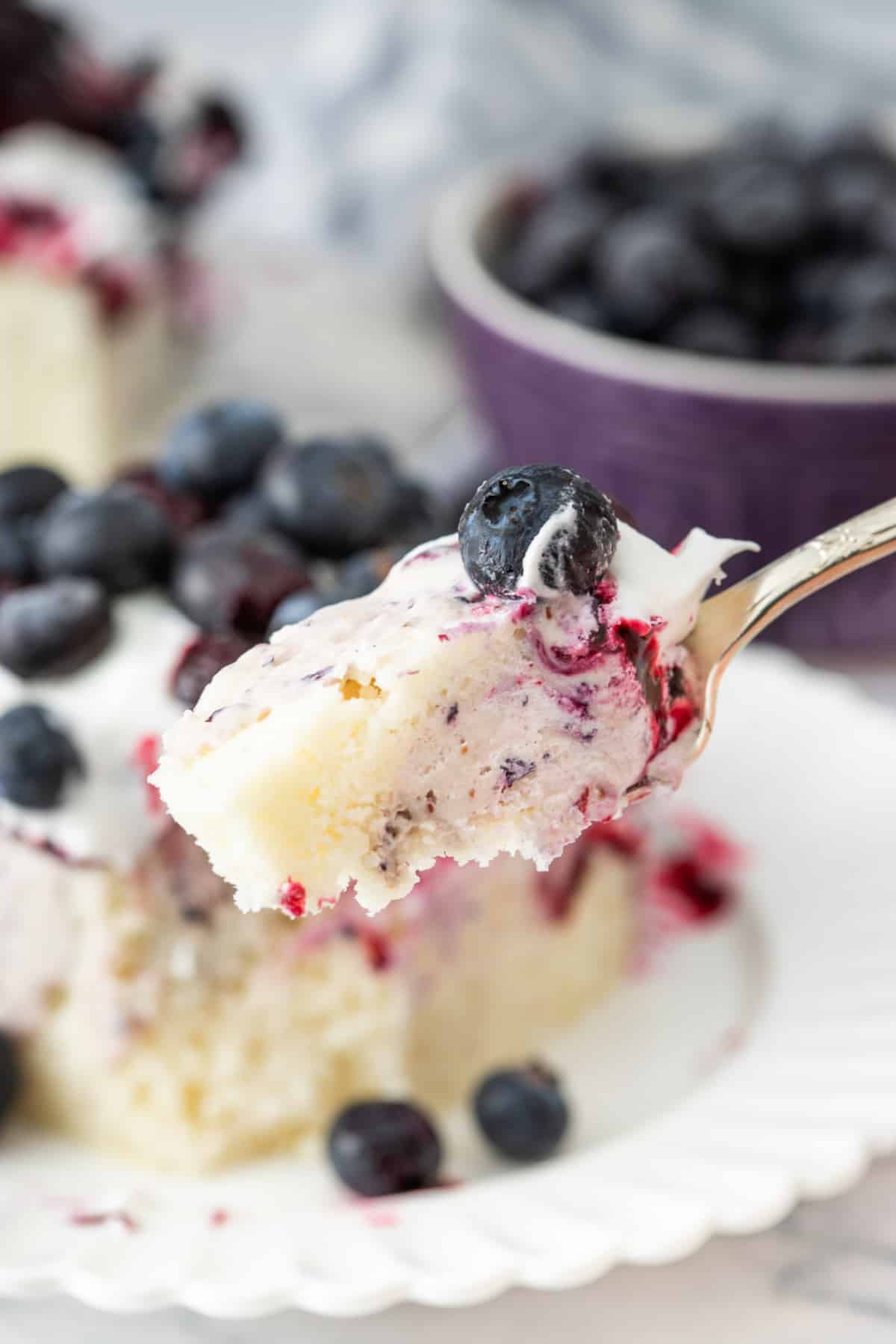 Blueberry Cheesecake Poke Cake Spoonful Spoonful of blueberry cheesecake poke cake with whipped topping and fresh blueberries