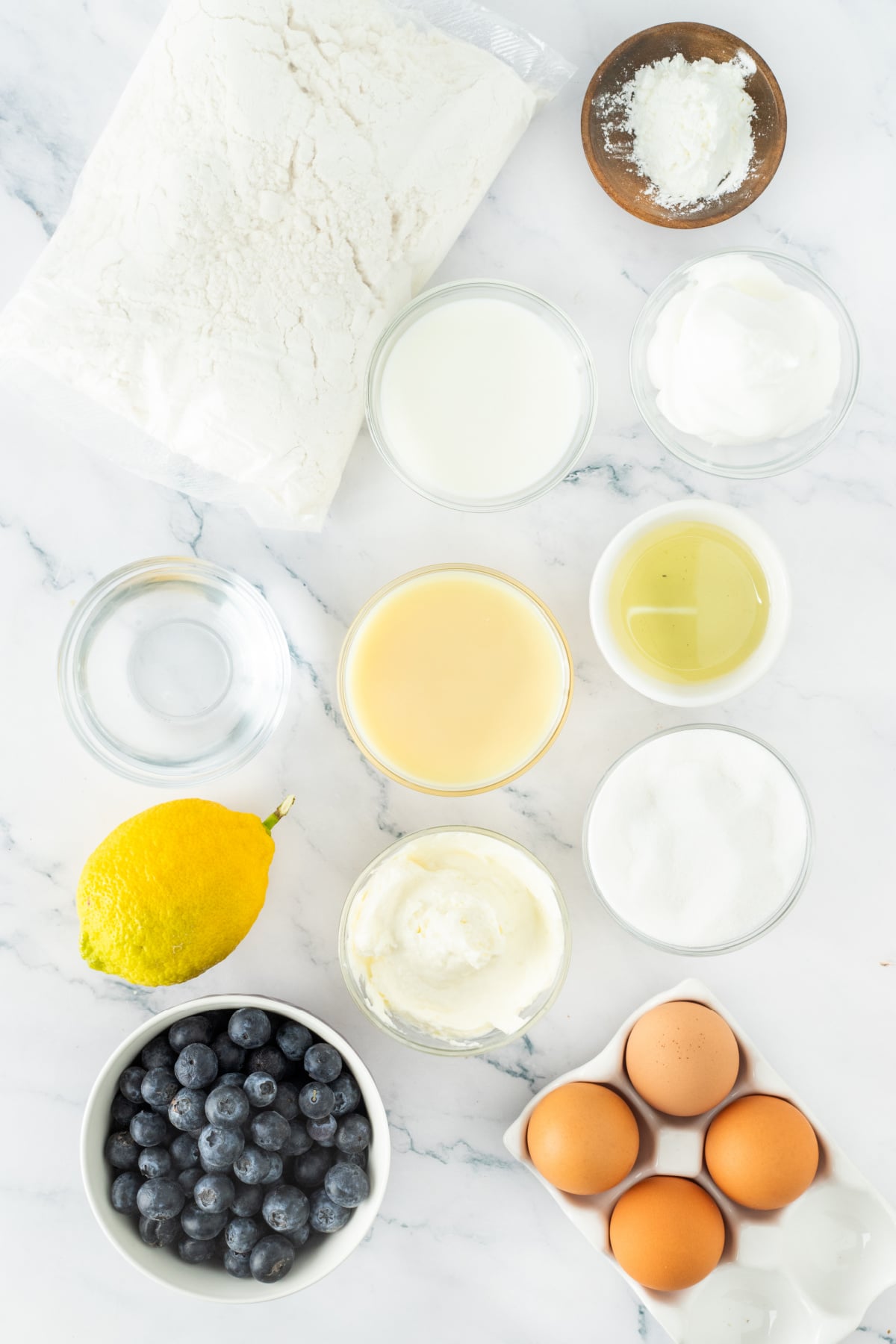 Blueberry poke cake ingredients Ingredients for blueberry poke cake including cake mix, blueberries, cream cheese, eggs, and lemon