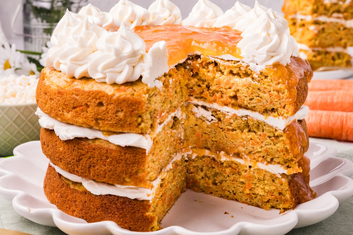 Carrot cake with apricot filling sliced view Carrot cake layers with apricot filling and cream cheese frosting on a white cake stand