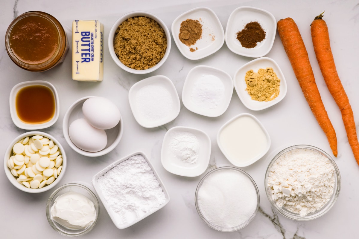 Carrot cake ingredients with apricot preserves and white chocolate Ingredients for carrot cake with apricot filling including fresh carrots, flour, sugar, spices, sour cream, butter, eggs, and white chocolate