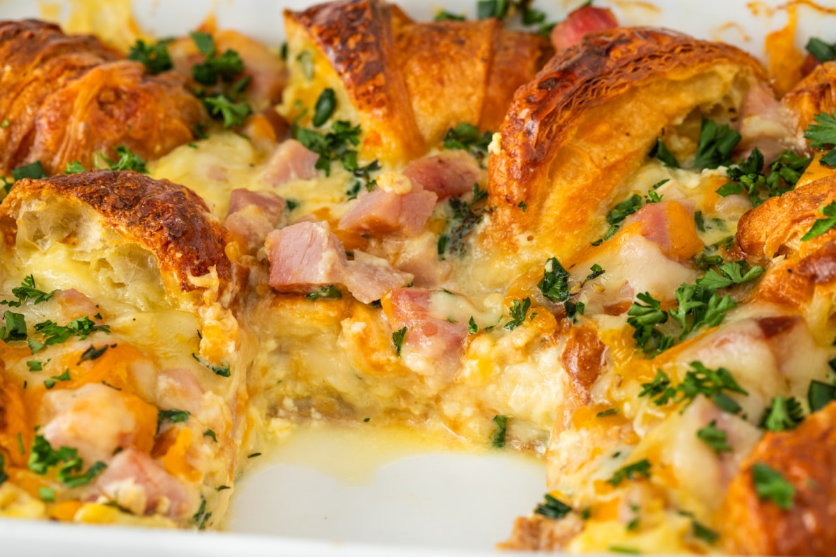 Croissant Breakfast Casserole with Ham and Cheese Close-Up close-up of croissant breakfast casserole with ham, melted Swiss and cheddar cheese, egg custard, and parsley baked until golden