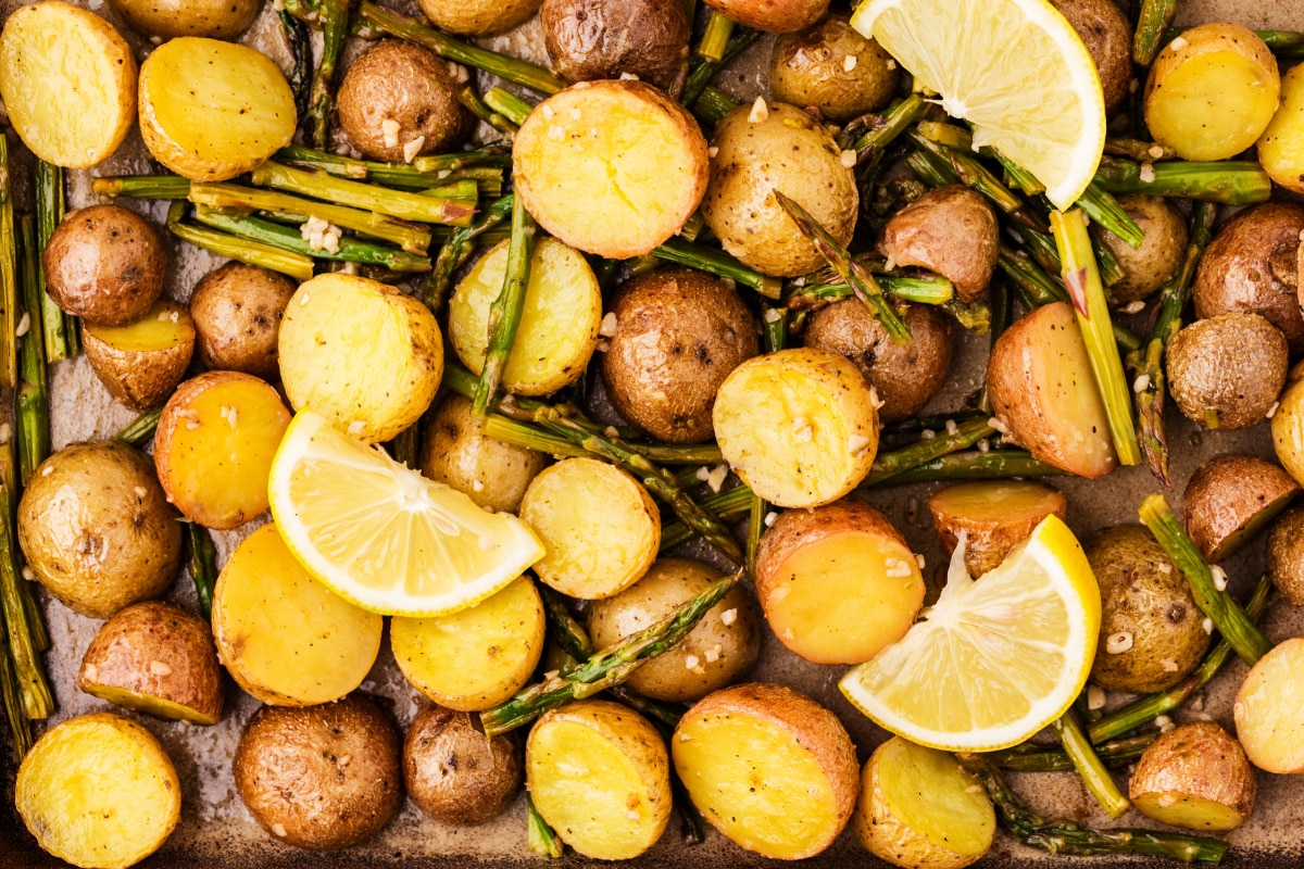 roasted potatoes and asparagus with lemon slices and garlic, golden baby potatoes and tender roasted asparagus close-up