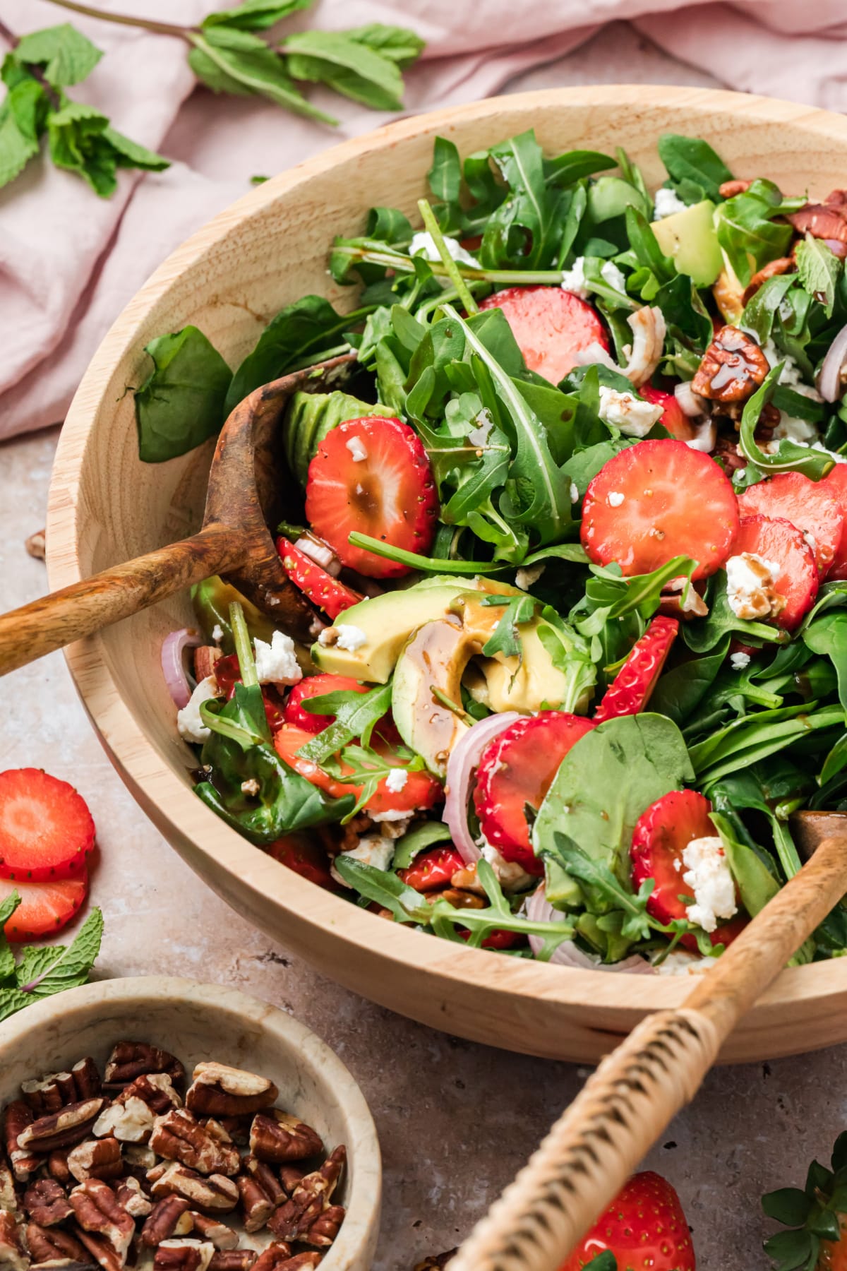 Strawberry Goat Cheese Salad with Avocado and Mixed Greens Strawberry goat cheese salad with avocado, pecans, and balsamic vinaigrette in a wooden bowl with spinach and arugula