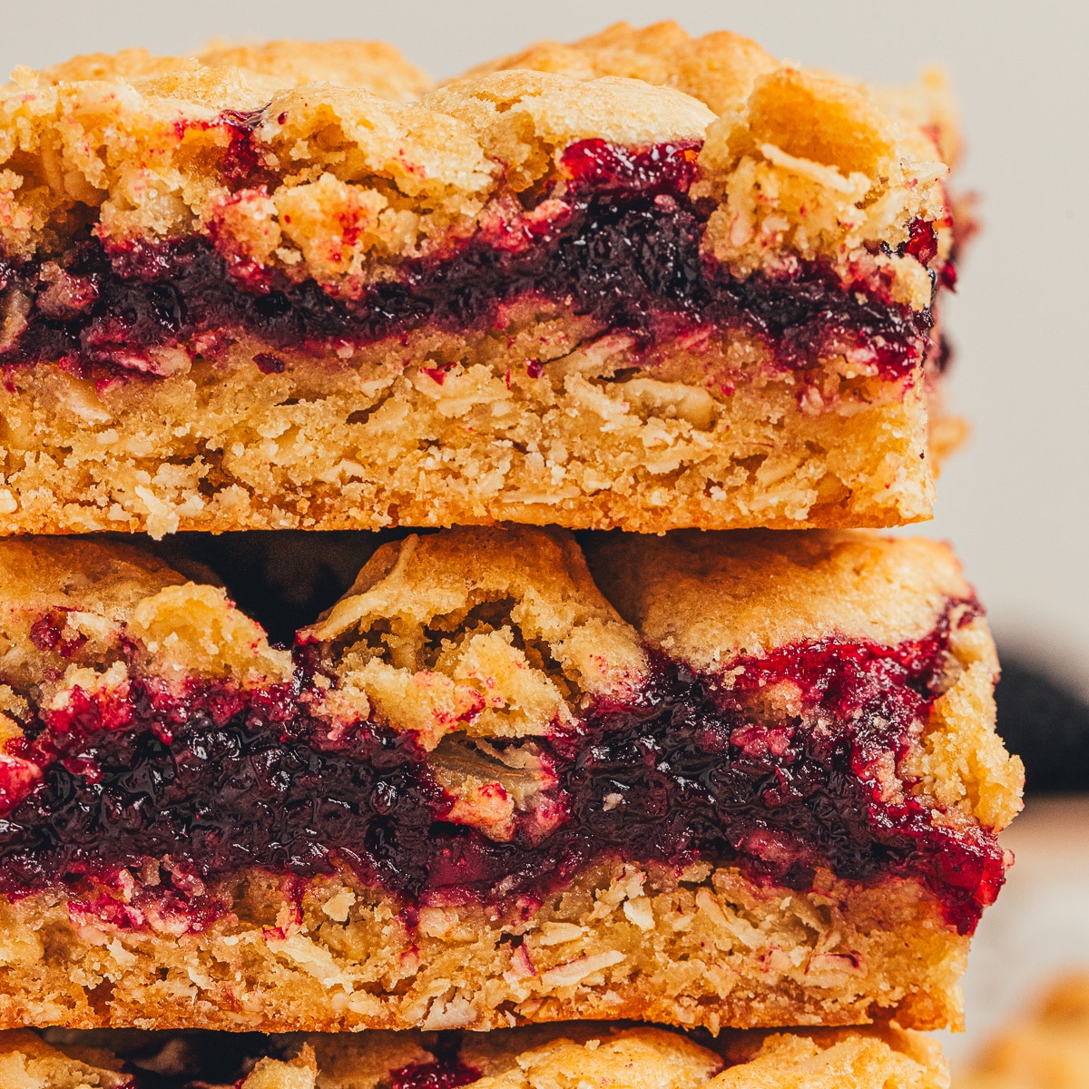 Blackberry crumble bars stacked with thick jam layer, oat crust, and crumb topping