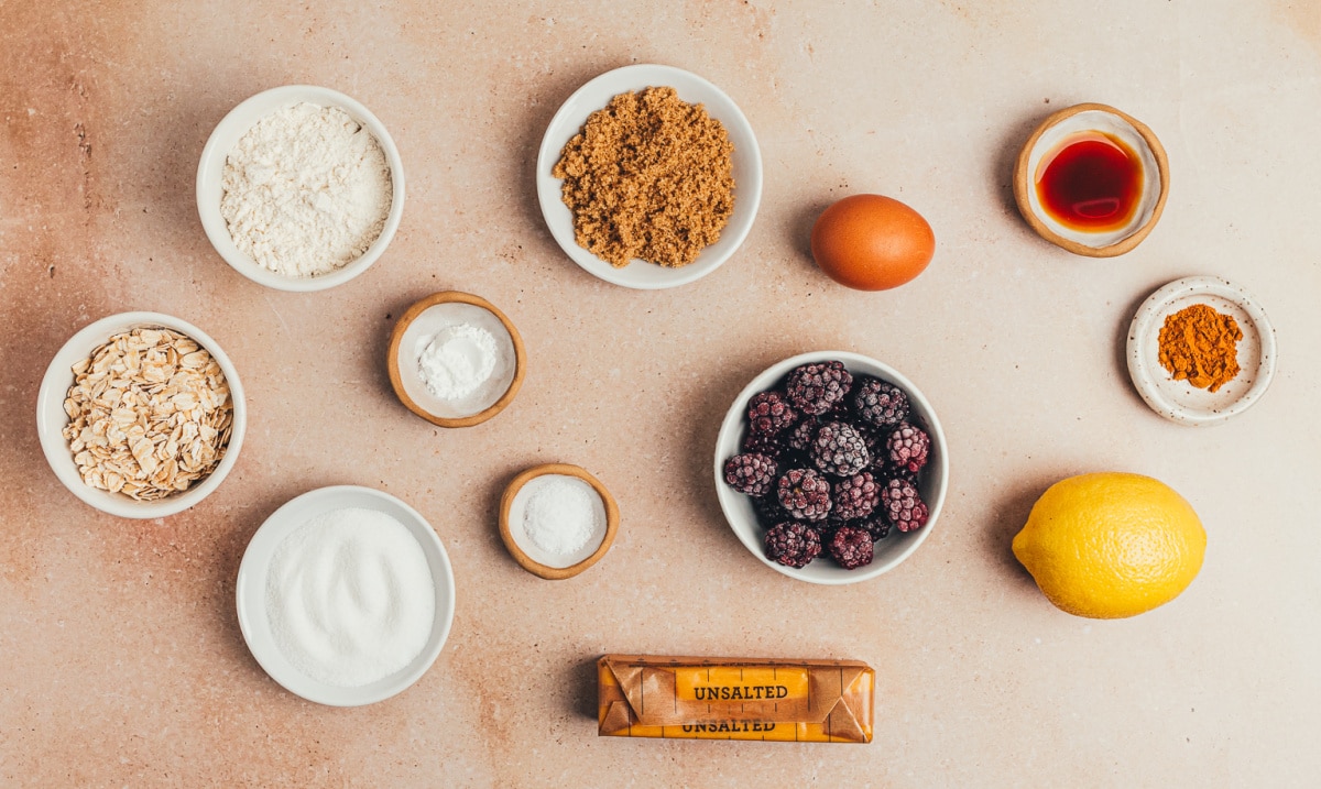 ingredients for blackberry oat crumble bars including blackberries, oats, flour, butter, sugar, and lemon