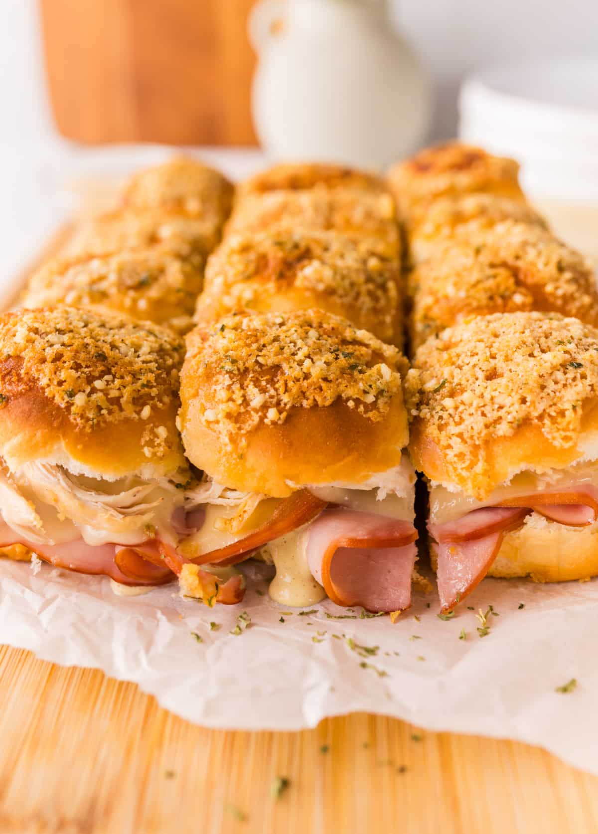 Close up of baked cordon bleu sliders with melted Swiss cheese, ham, shredded chicken, and crispy garlic panko topping