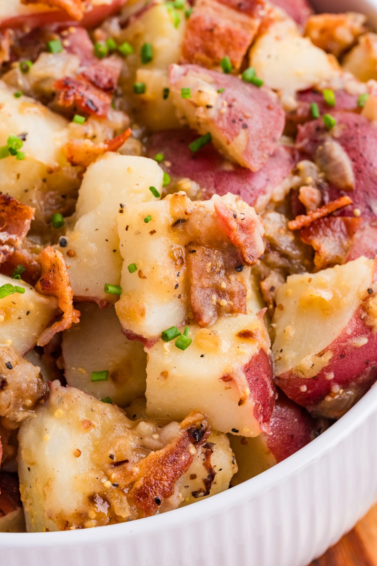 German potato salad with bacon and two mustards German potato salad with bacon, red potatoes, and whole grain mustard dressing garnished with chives