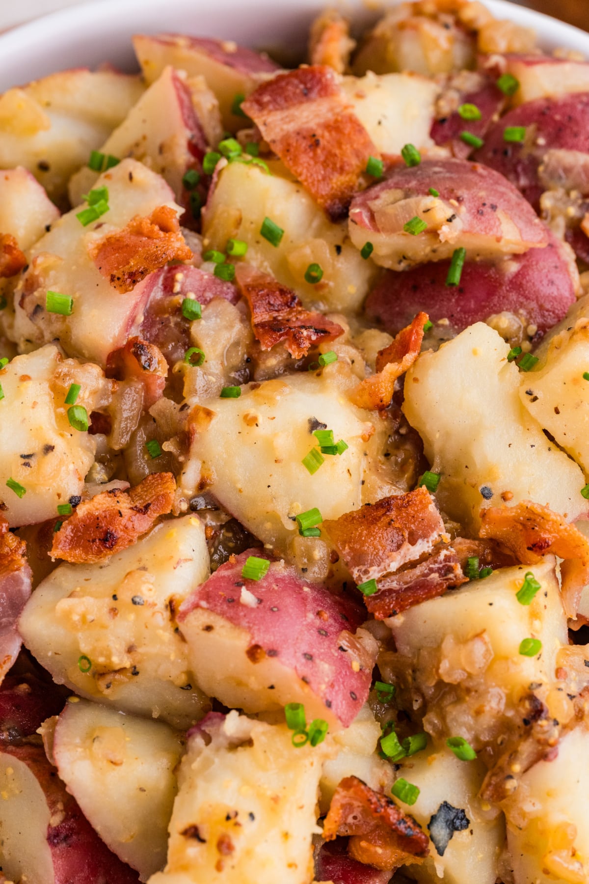 close-up german potato salad with bacon and mustard German potato salad close-up with bacon, red potatoes, whole grain mustard, and chives
