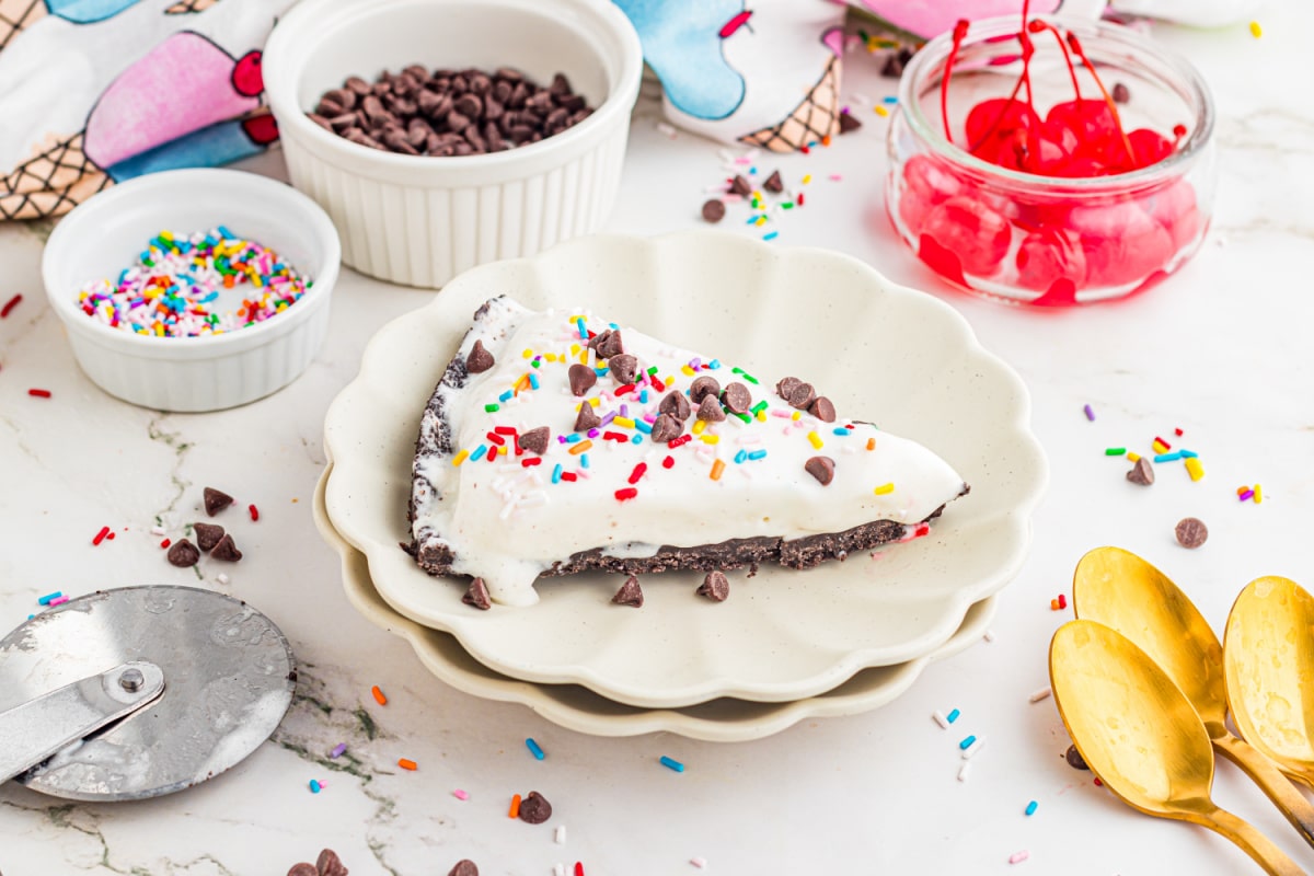 slice of ice cream pizza on a plate with Oreo crust, sprinkles, and chocolate chips