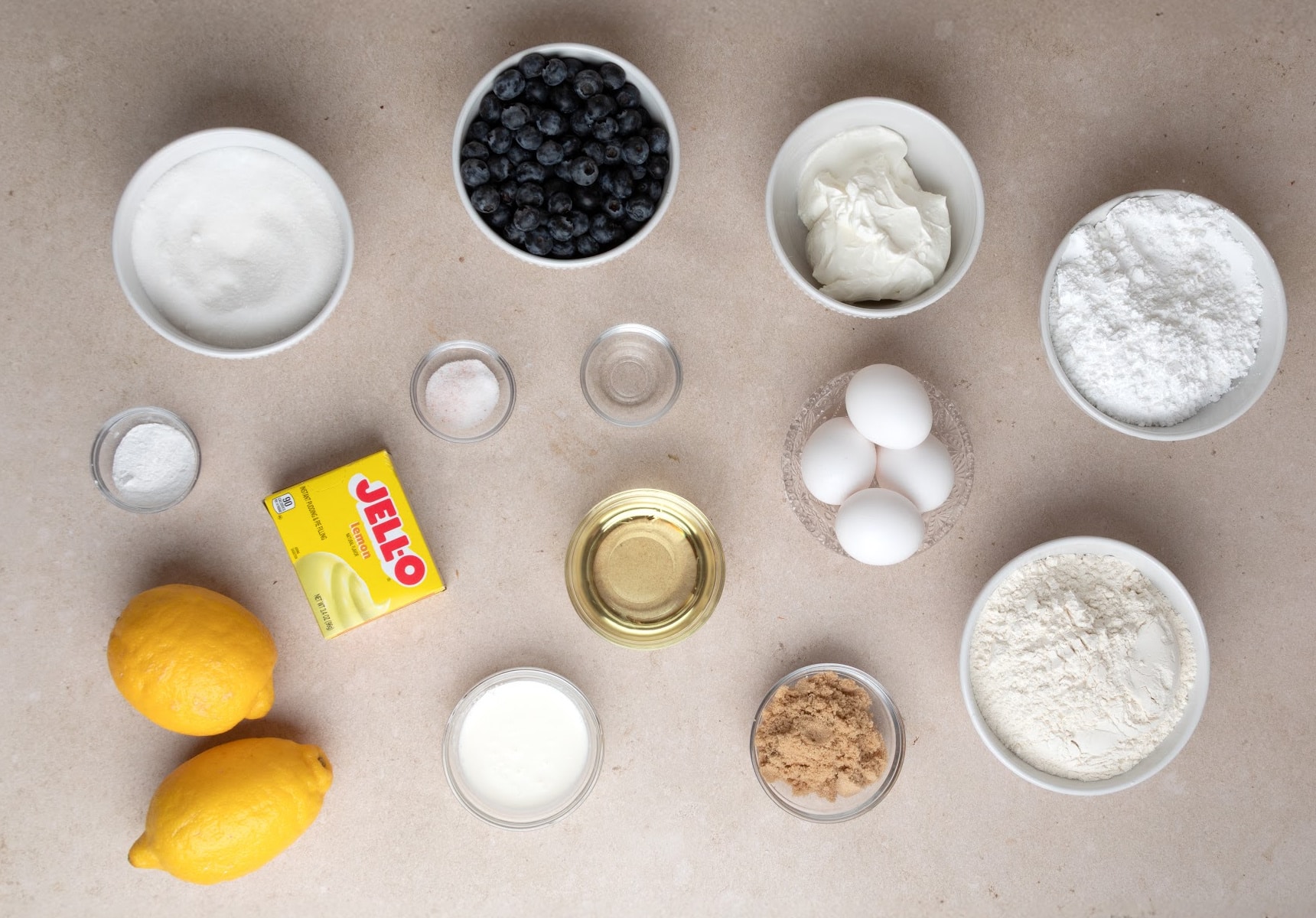 ingredients for lemon blueberry bundt cake including flour, sugar, eggs, sour cream, blueberries, and lemon pudding mix