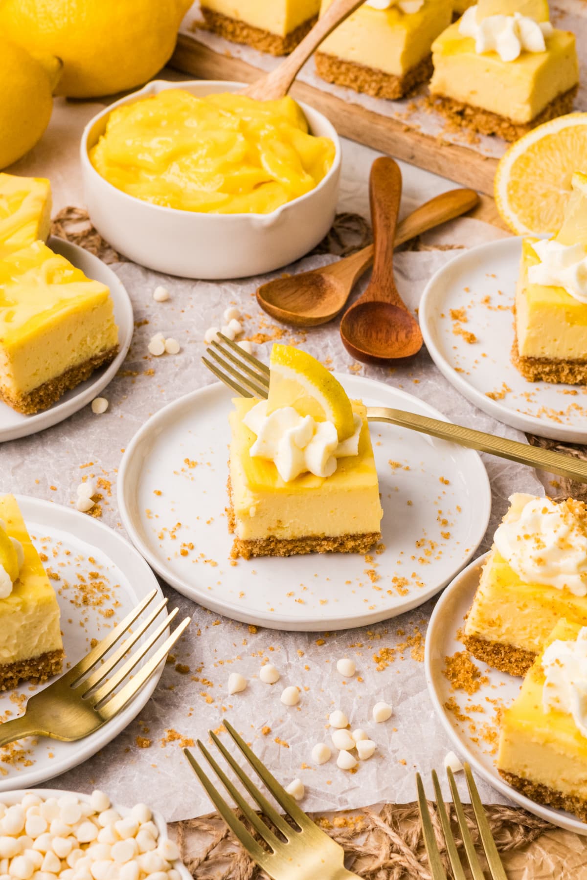 lemon cheesecake bars served on plates with lemon slices whipped cream and lemon curd