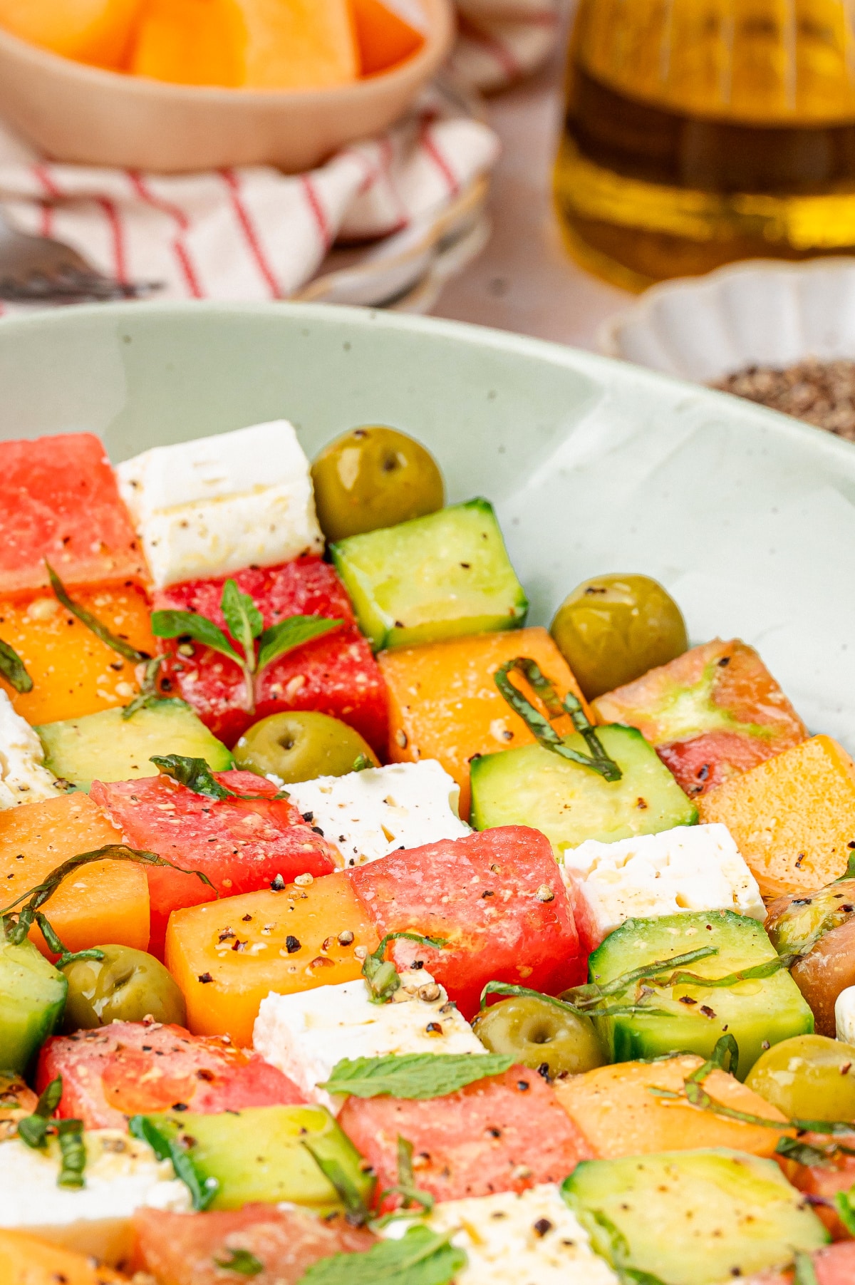 melon and feta salad with cucumber, olives, and fresh herbs in a bowl