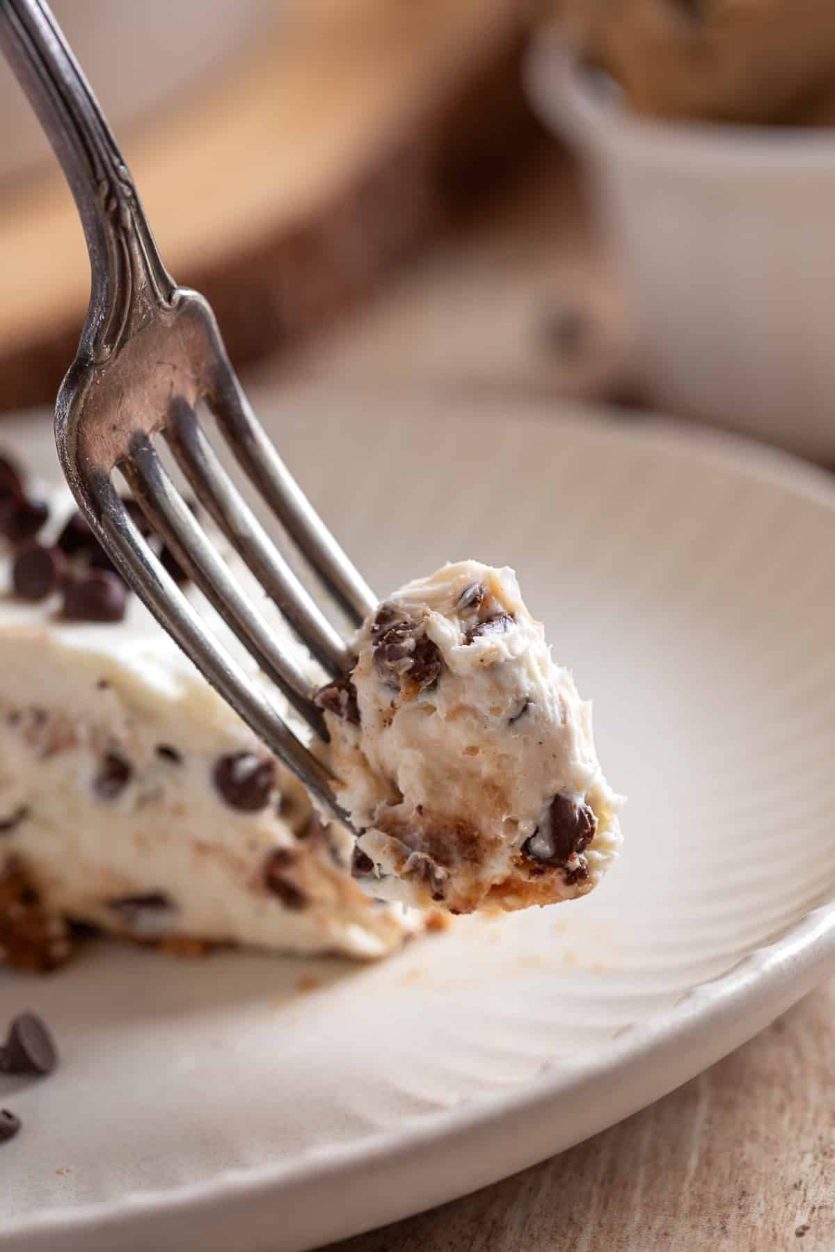 fork holding a bite of no-bake cheesecake with chocolate chips and cookie crust