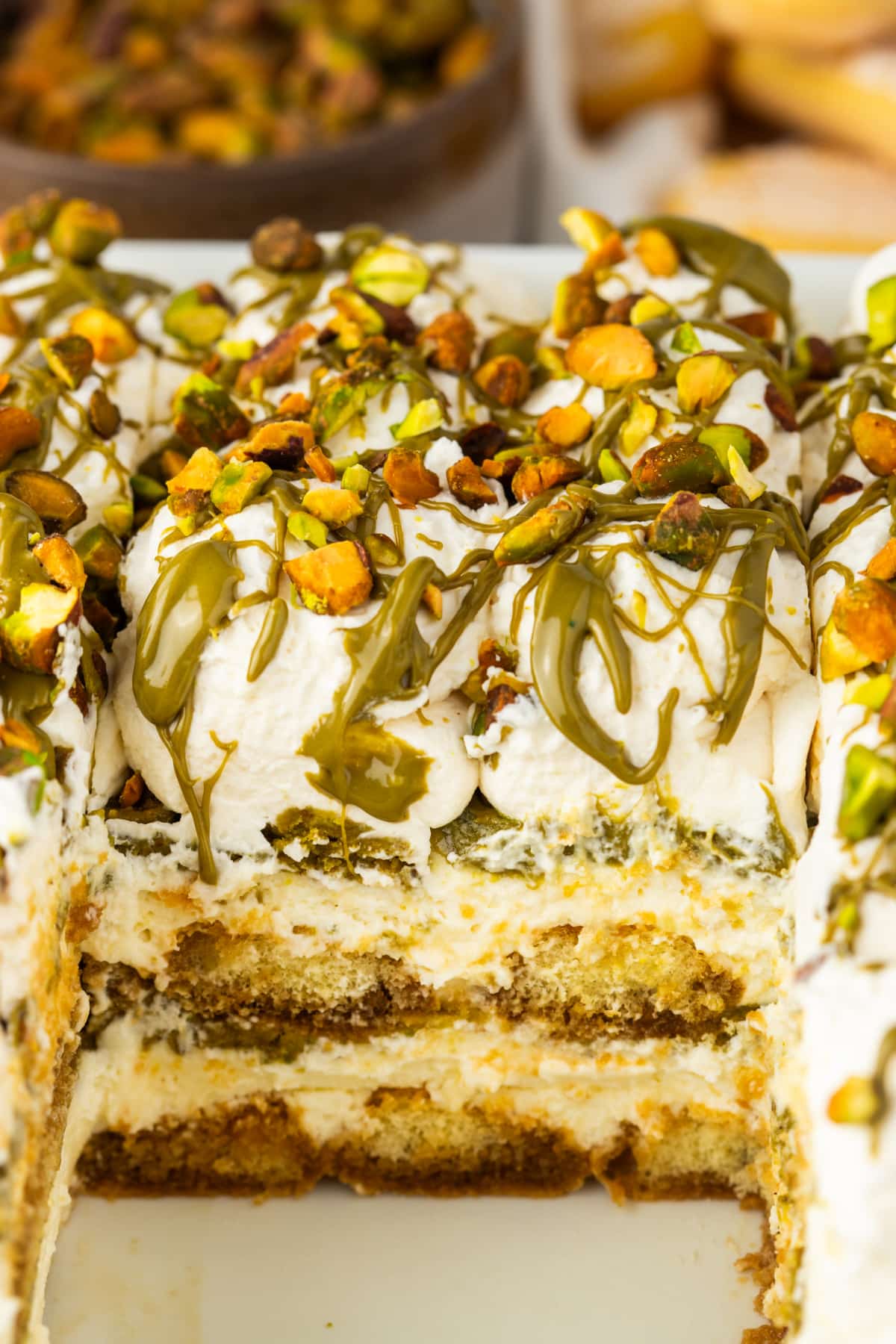 Tiramisu Slice Showing Creamy Layers and Pistachio Filling slice of tiramisu showing layers of mascarpone cream espresso soaked ladyfingers and pistachio cream with whipped topping and chopped pistachios
