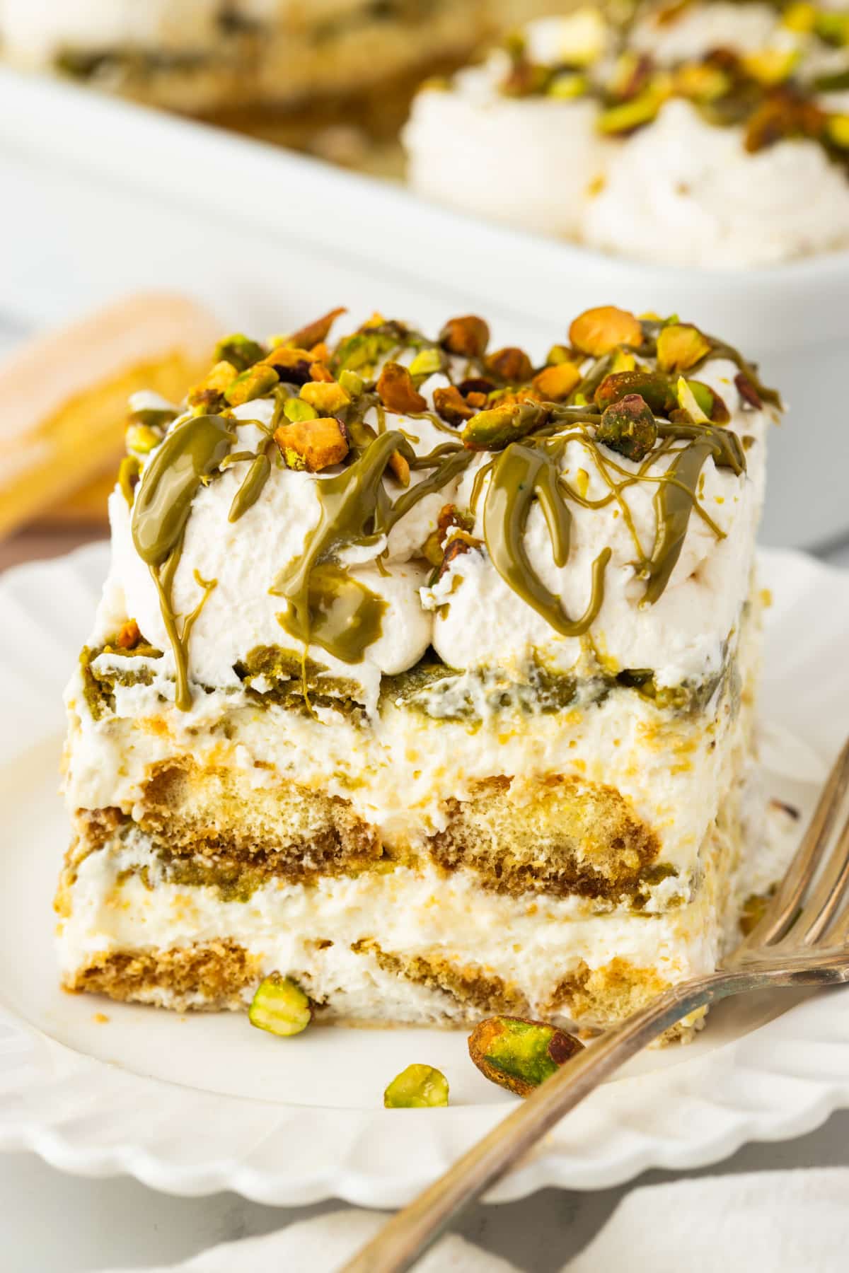 Tiramisu Slice with Pistachio Drizzle and Creamy Layers slice of tiramisu with mascarpone layers espresso soaked ladyfingers pistachio cream drizzle and chopped pistachios on top