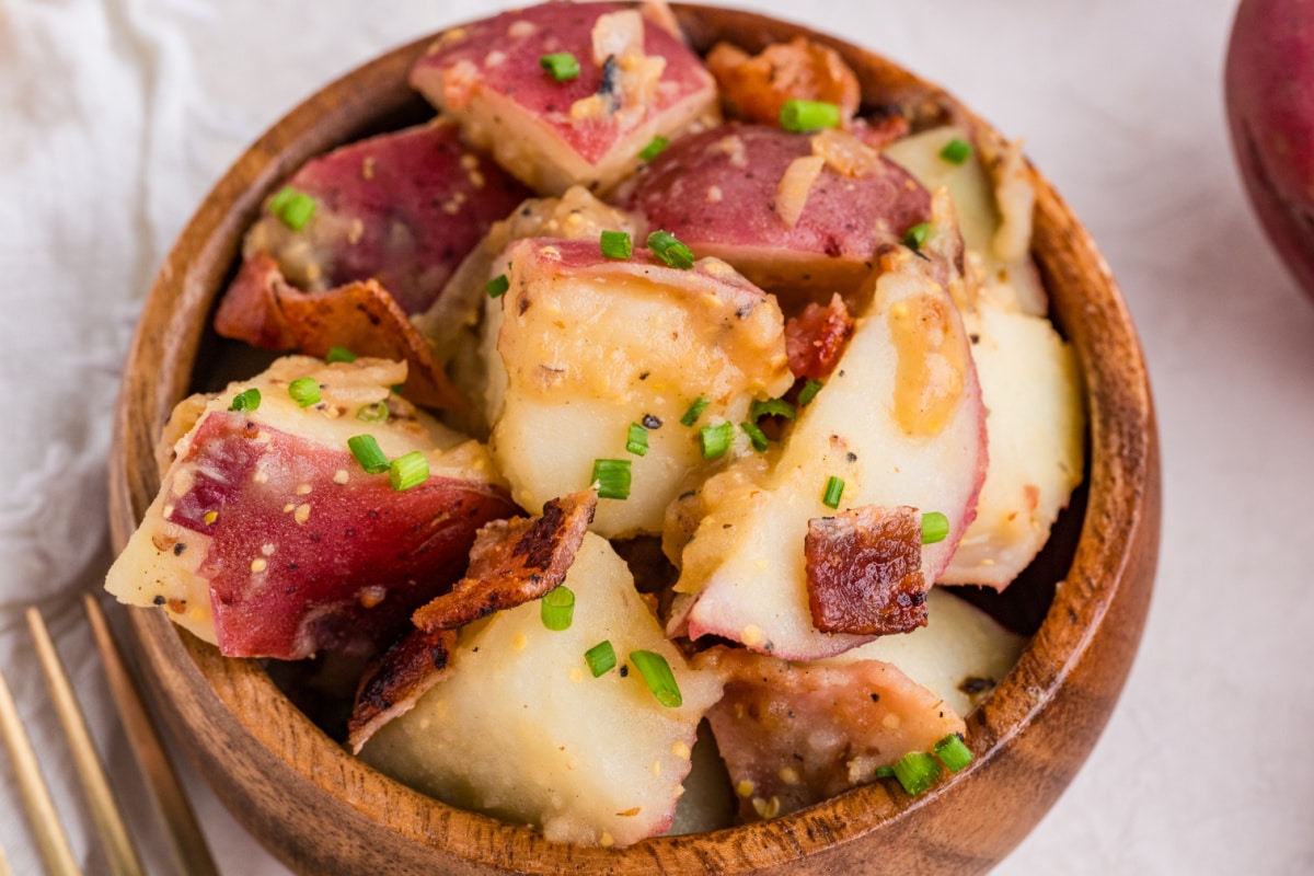 warm potato salad with bacon and mustard dressing red potato salad with bacon, whole grain mustard dressing, and fresh chives in a wooden bowl