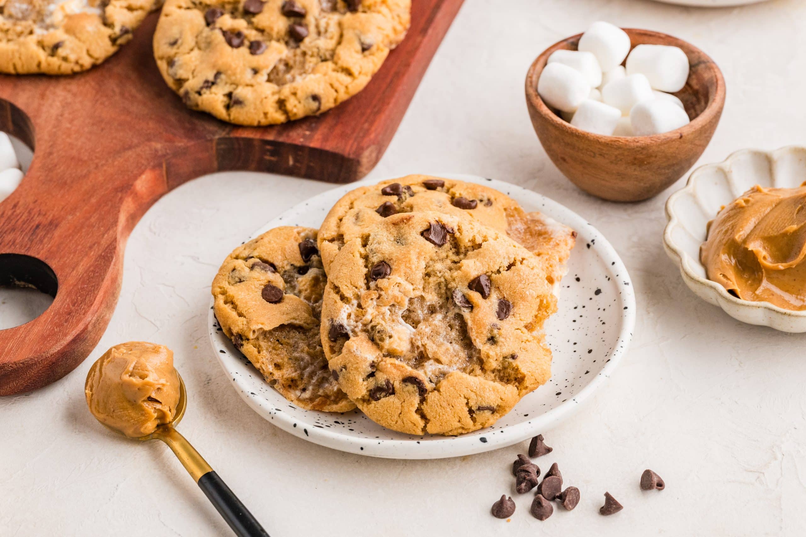 Soft peanut butter cookies with toasted marshmallow pockets and mini chocolate chips stacked on a white plate.