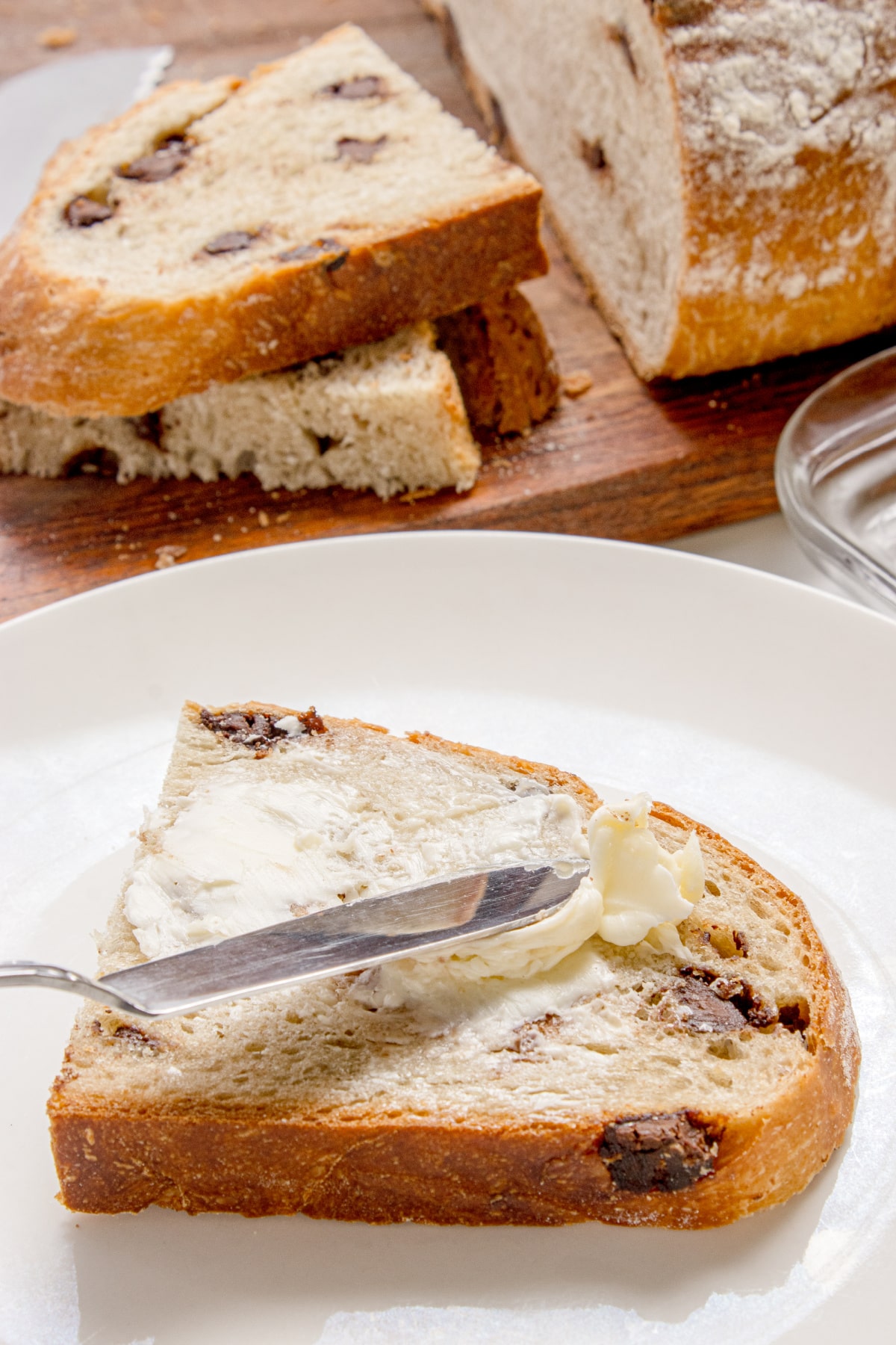 slice of chocolate chip bread with butter spread on top on a plate