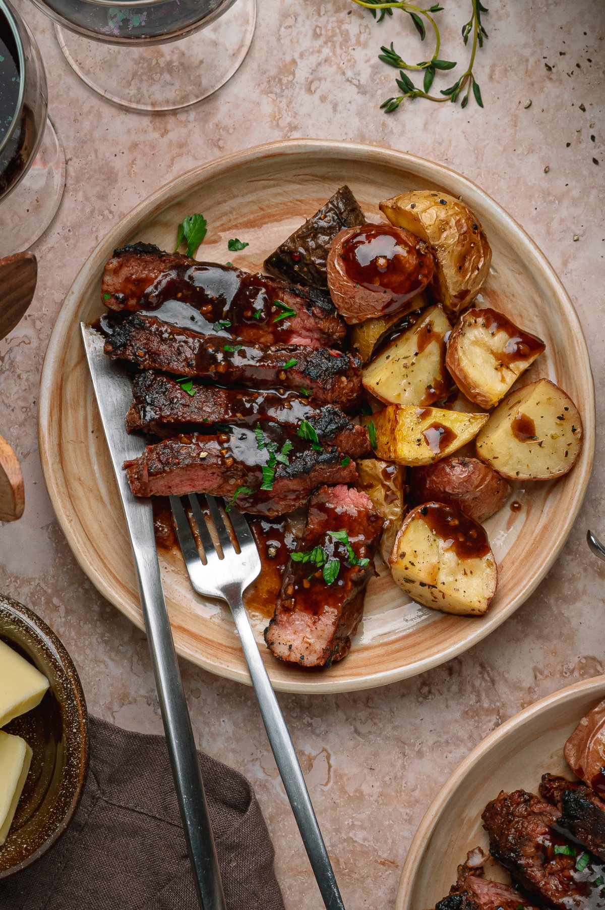 Cocoa rubbed steak sliced and finished with dark stout pan sauce beside roasted potatoes. Cocoa rubbed steak with dark stout pan sauce served sliced with roasted potatoes on a dinner plate.