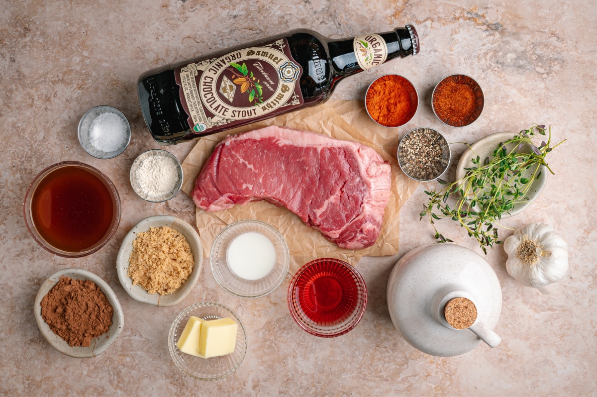 Ingredients laid out for cocoa rubbed steak and dark stout pan sauce. Ingredients for cocoa rubbed steak including New York strip steak, cocoa powder, chocolate stout, spices, and beef broth.