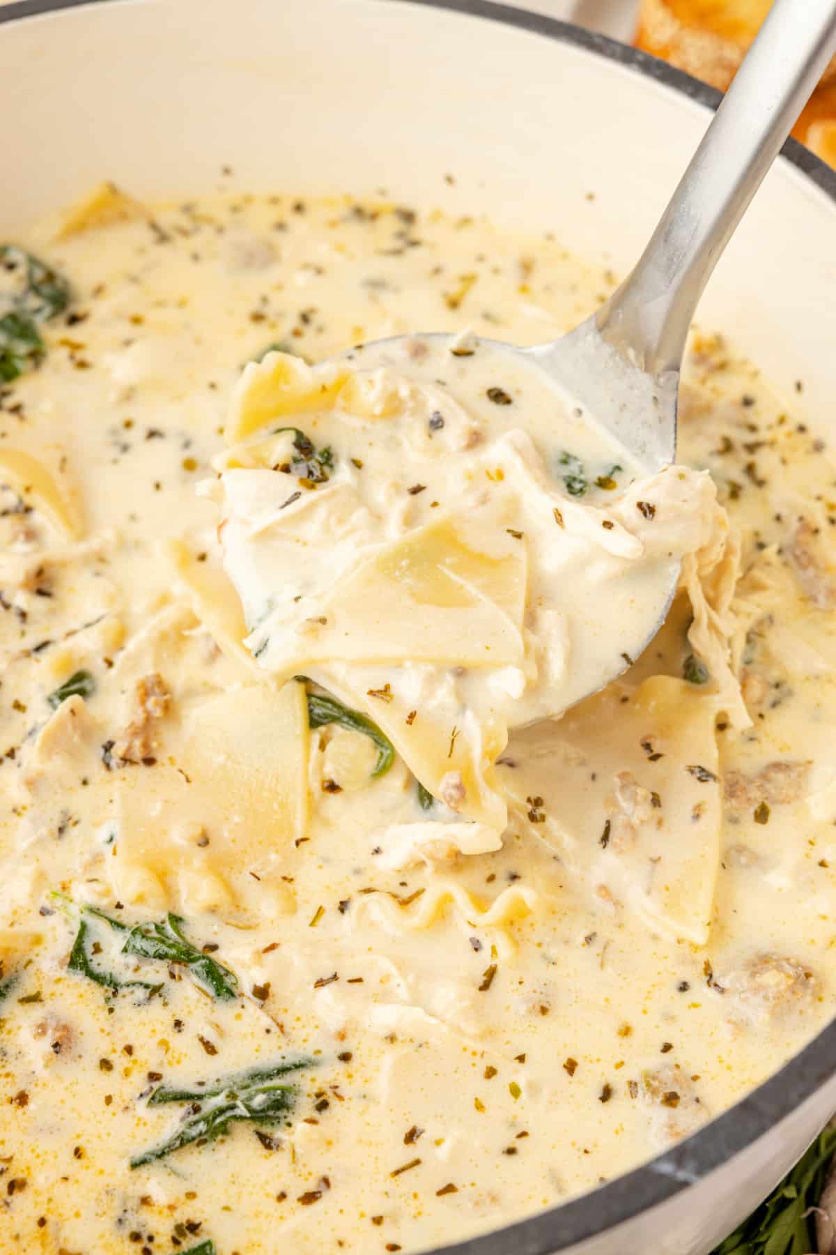 Creamy lasagna soup with ricotta, chicken, sausage, spinach, and broken lasagna noodles in a creamy white broth