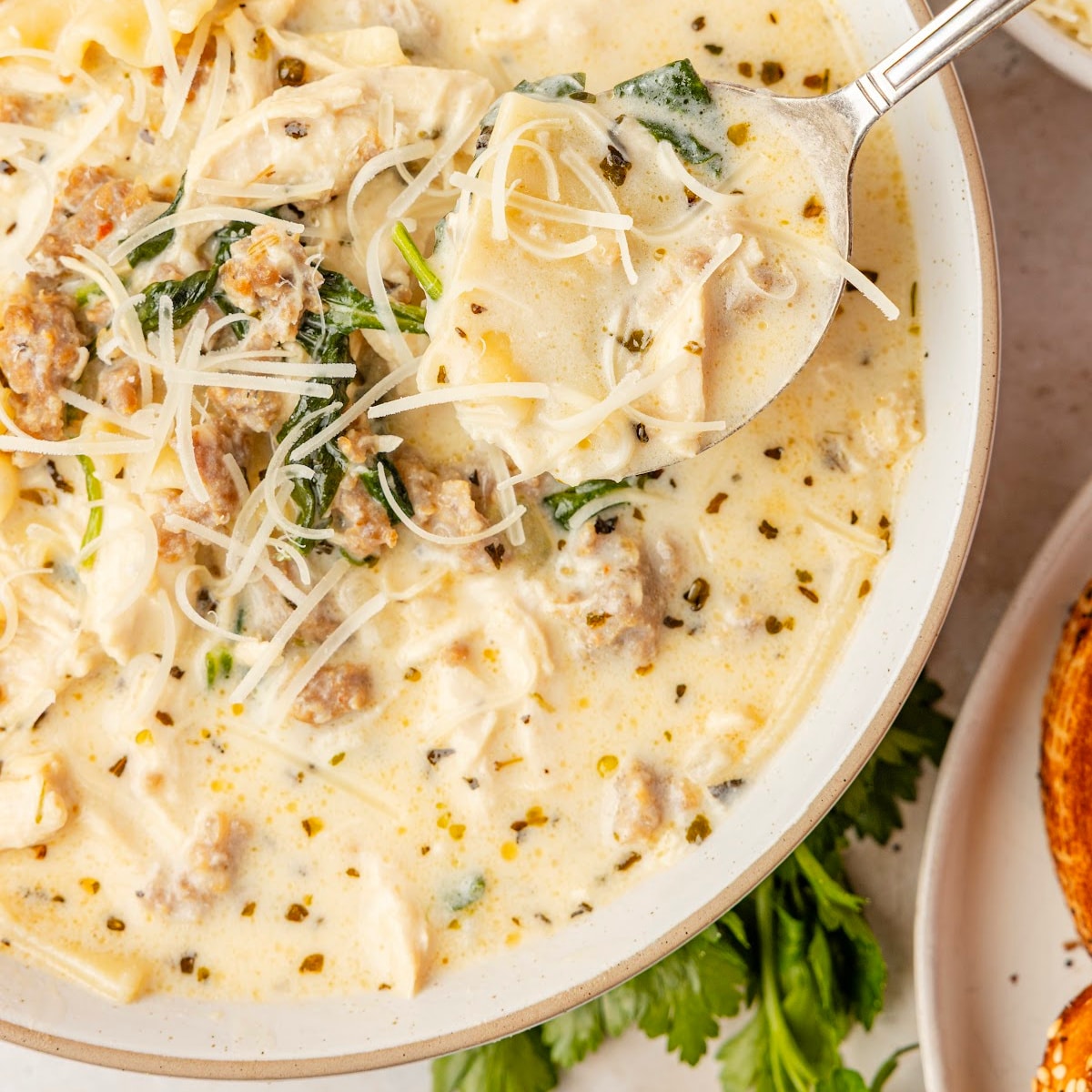 White Lasagna Soup made with sausage, chicken, ricotta, mozzarella, spinach, and broken lasagna noodles in creamy broth